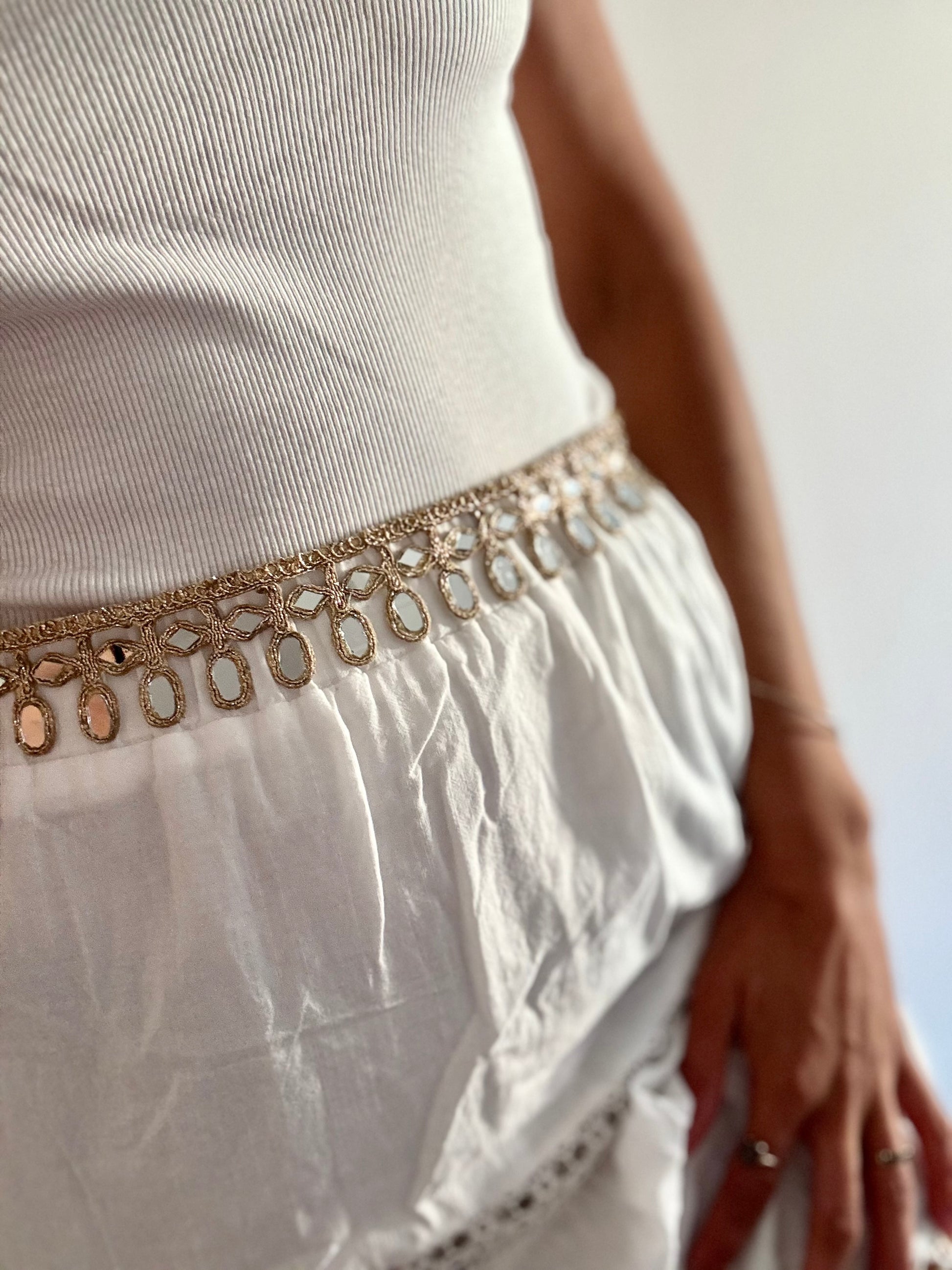 White skirt with a gold belt featuring circular patterns on a blurred background