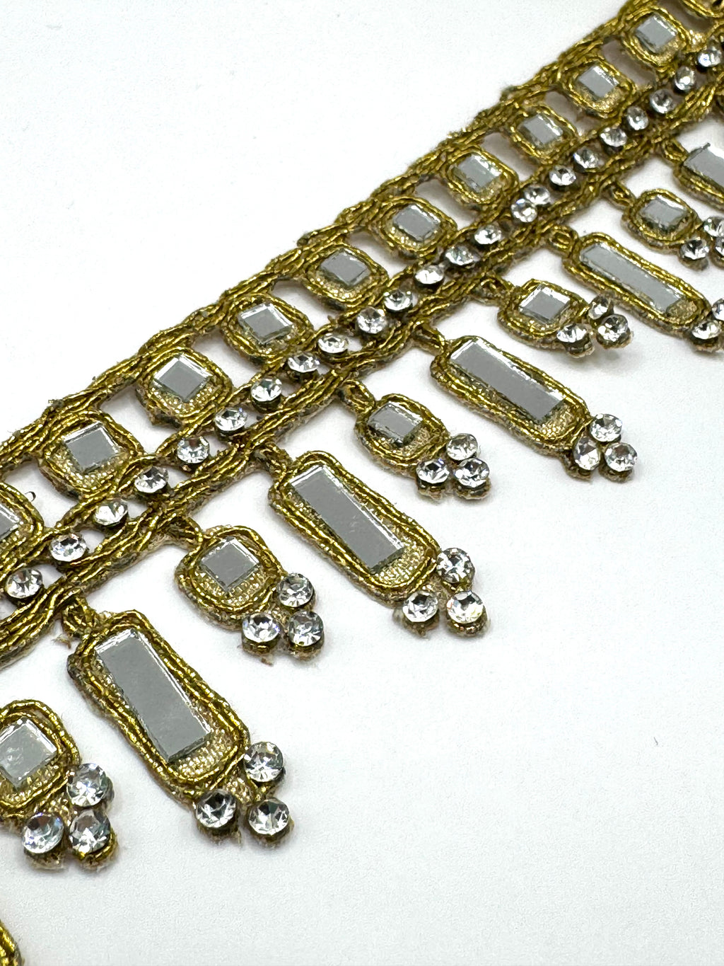 Decorative gold and silver trim with rectangular stones on a white background