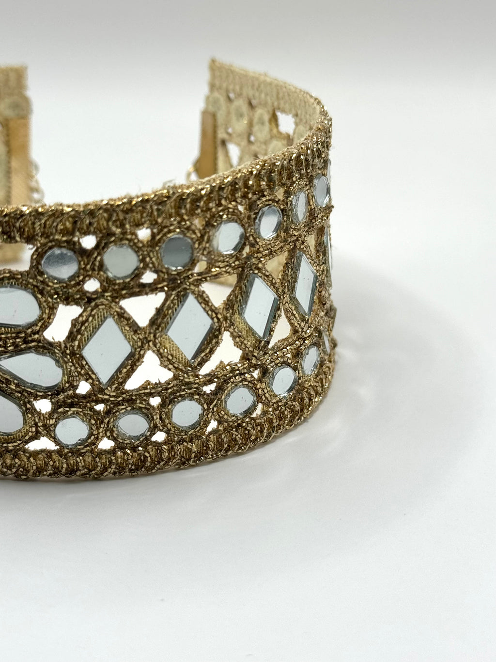 Gold bracelet with mirror-like stones on a white background