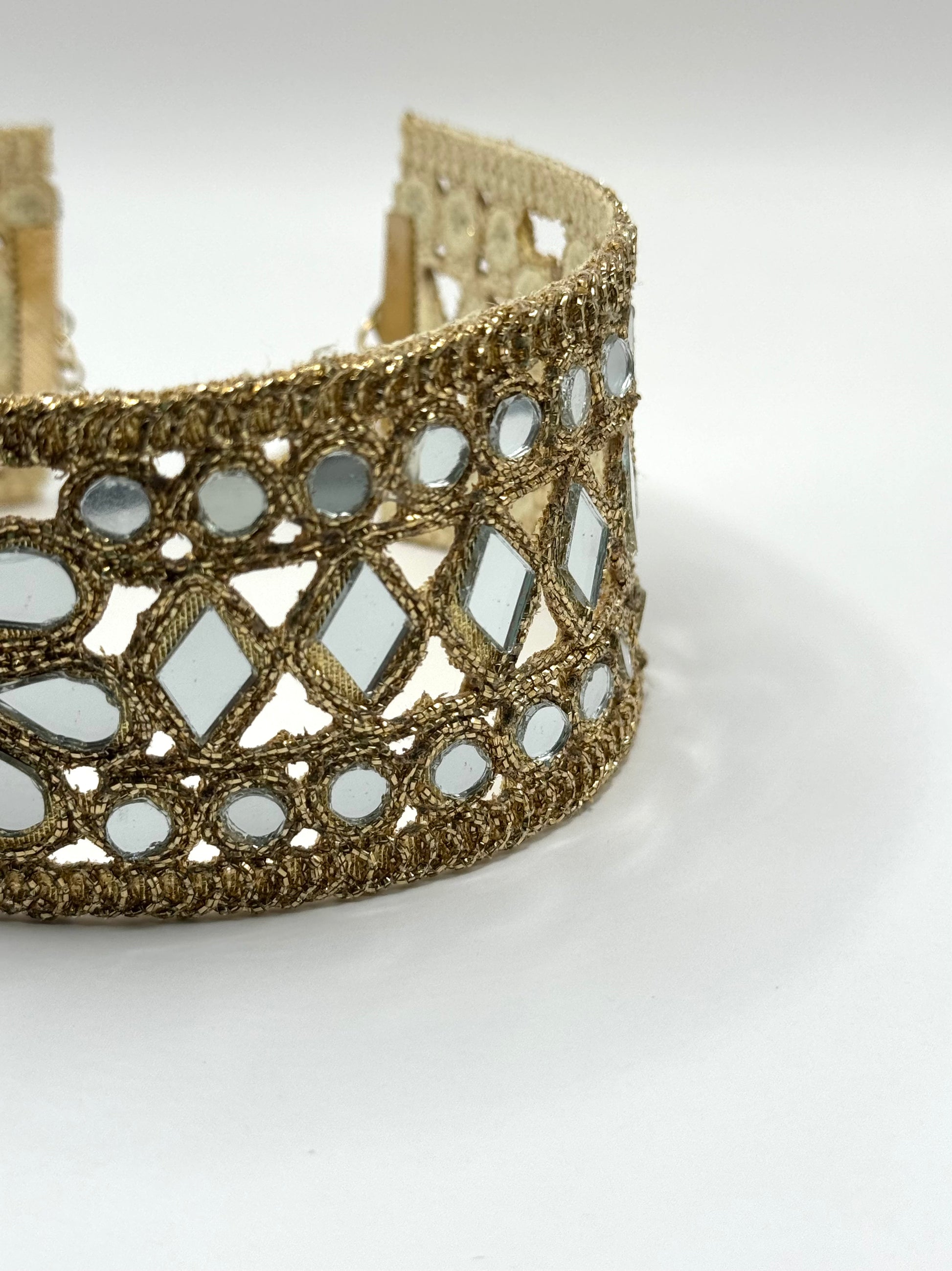 Gold bracelet with mirror-like stones on a white background