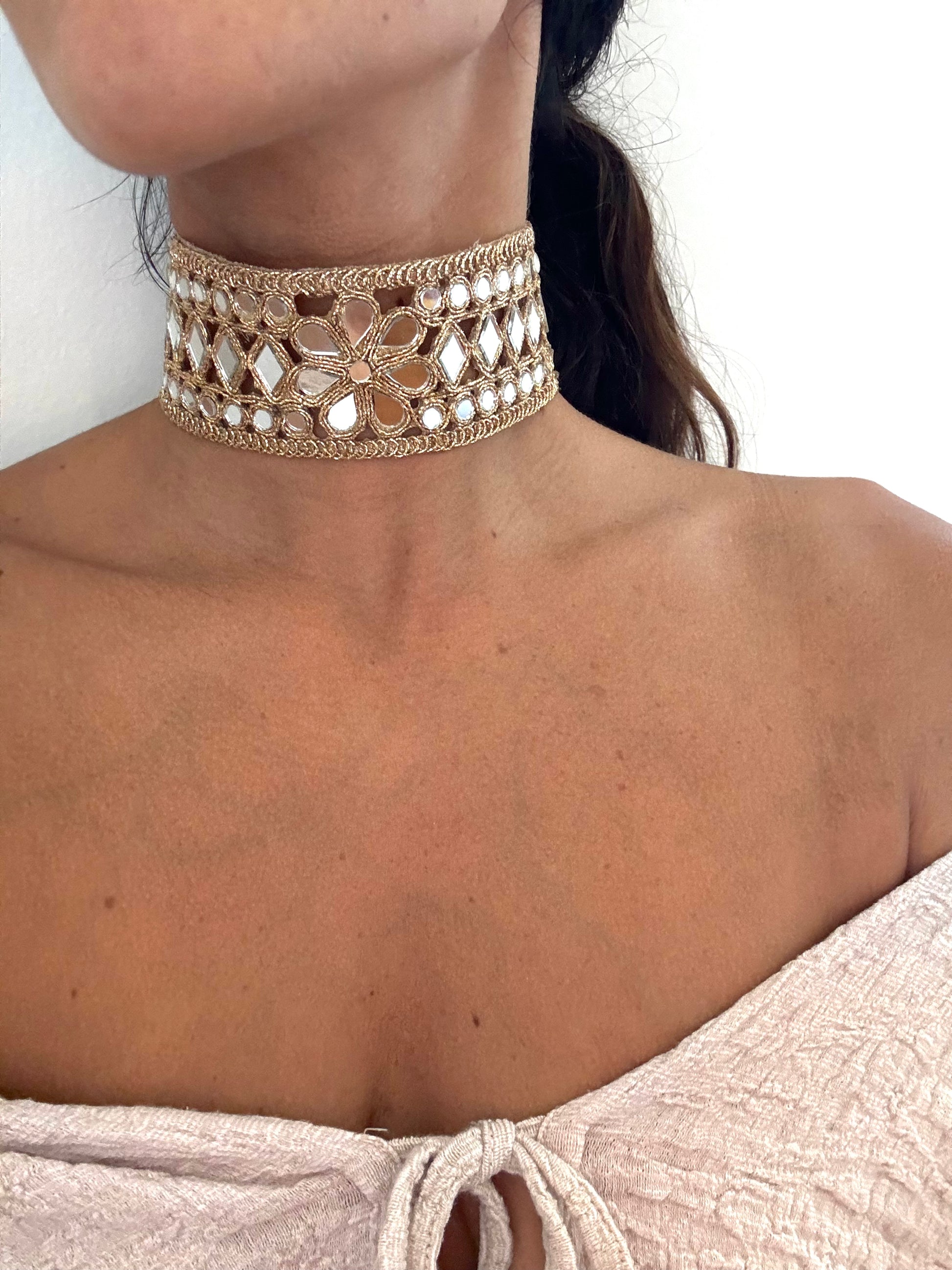 Close-up of a person wearing a decorative choker necklace with a neutral background