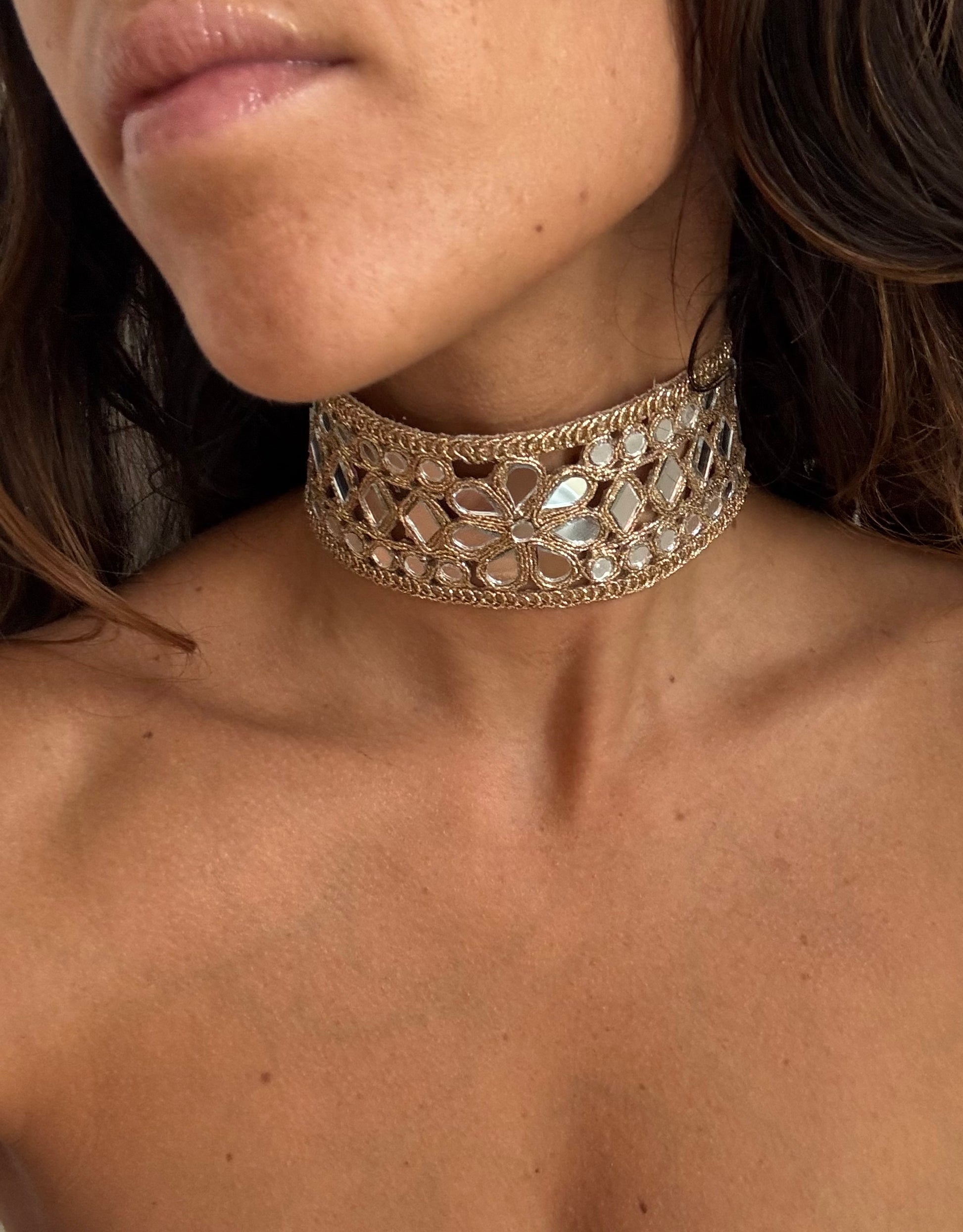 Close-up of a person wearing a decorative gold choker necklace.