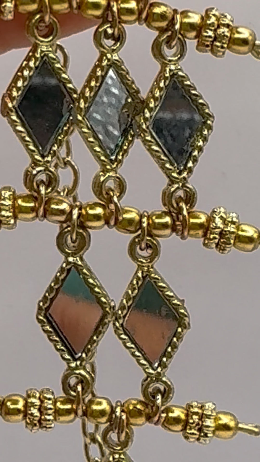 Gold earrings with black and brown gemstones on a gray background