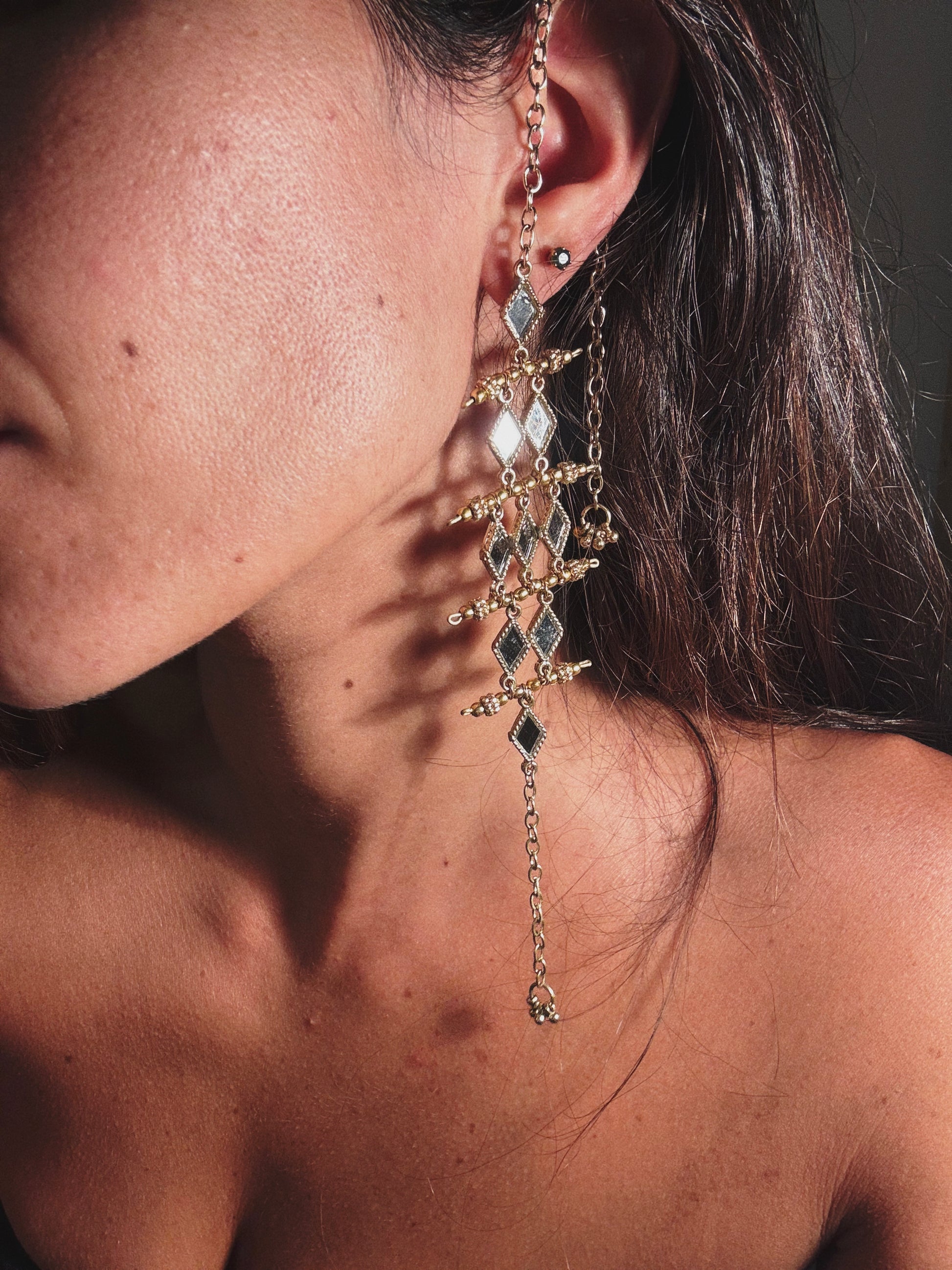 Close-up of a person wearing an elegant earring with gemstones.
