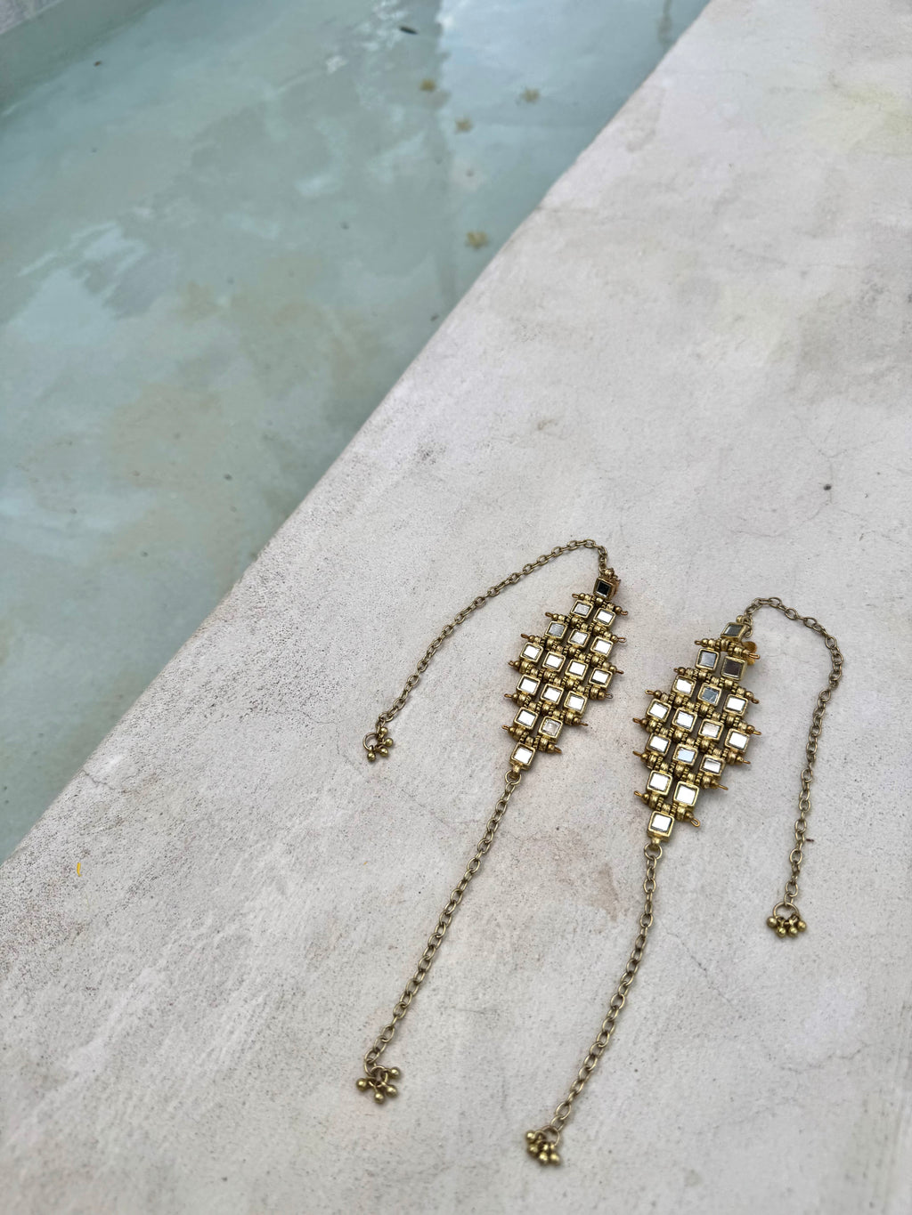 Pair of gold earrings on a textured surface