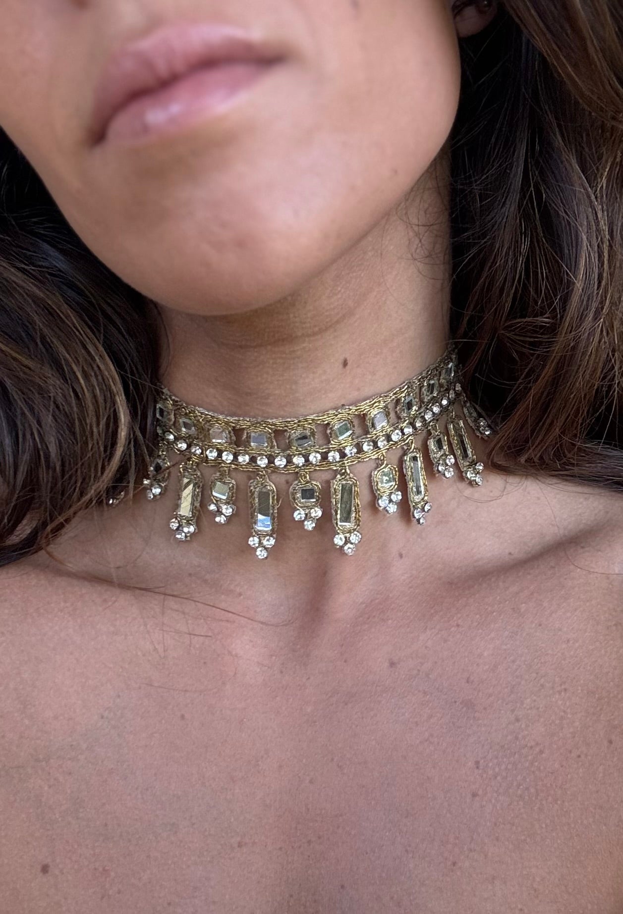 Close-up of a person wearing a gold necklace with dangling beads.