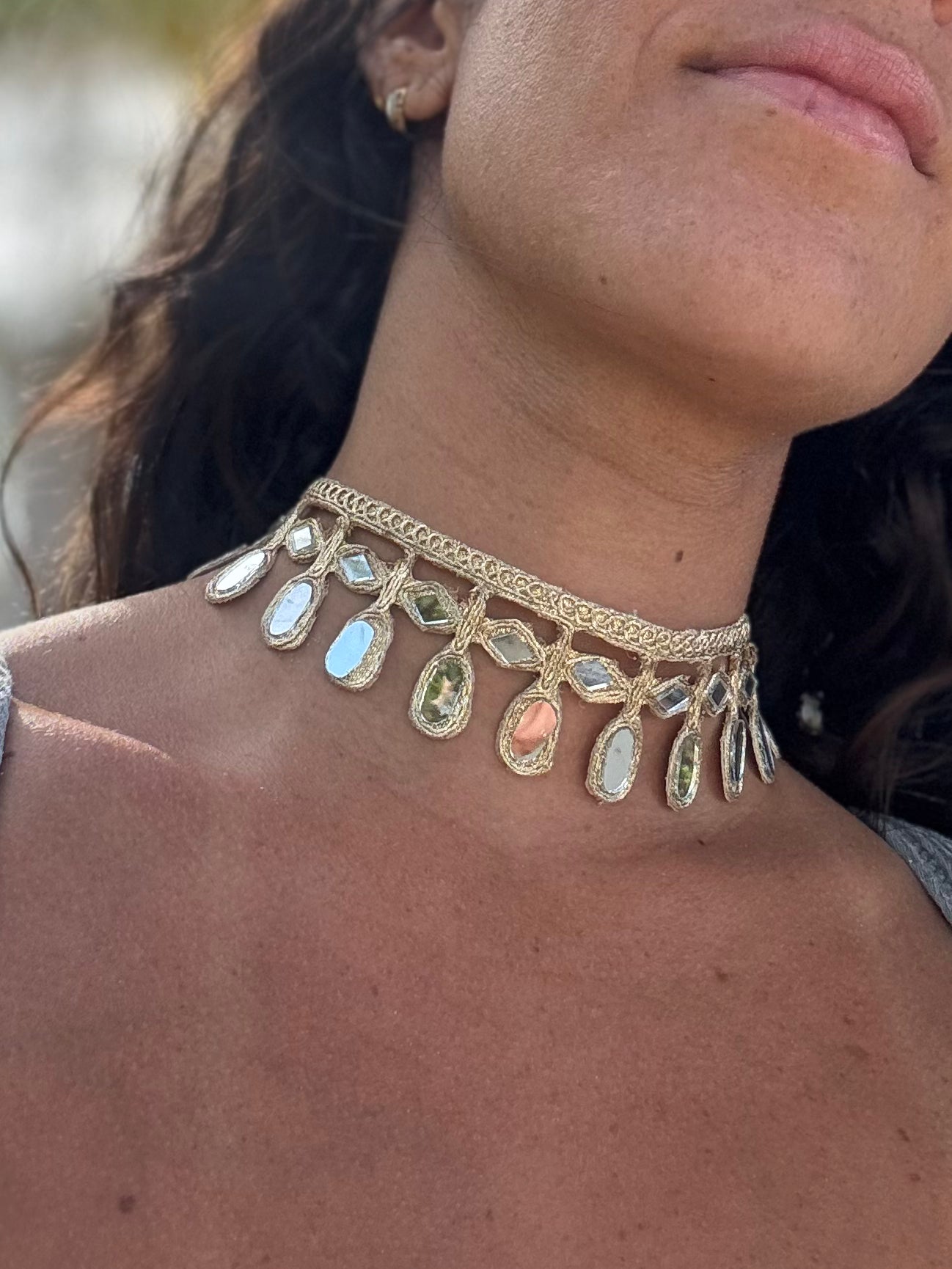 Close-up of a woman wearing a gold choker necklace with gemstones.