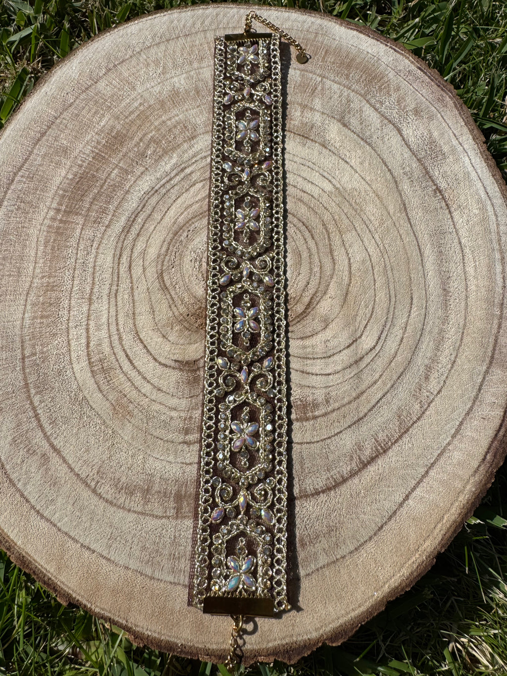 Decorative bracelet on a wooden stump with grass in the background