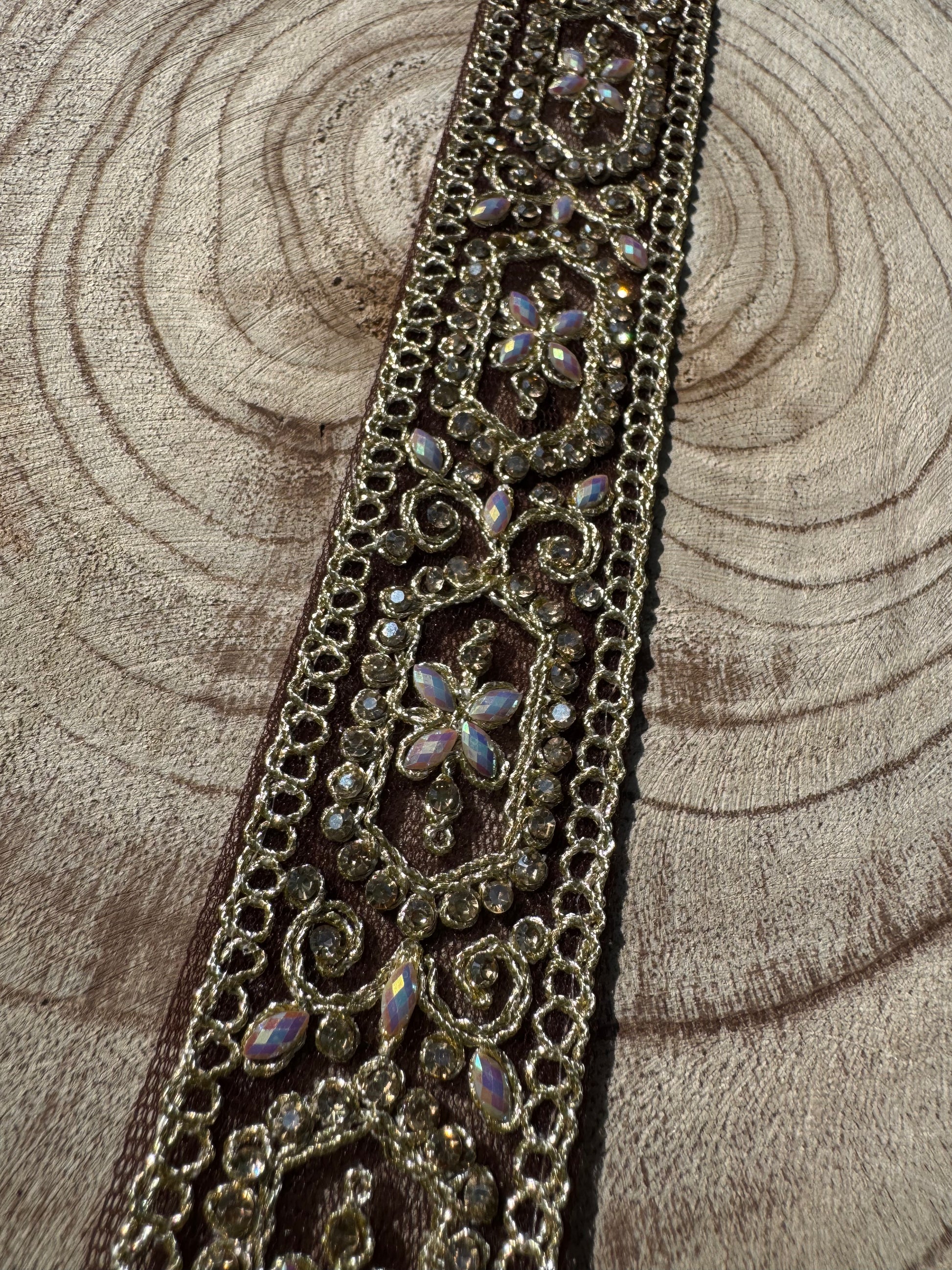 Decorative lace trim with rhinestones on a wooden surface