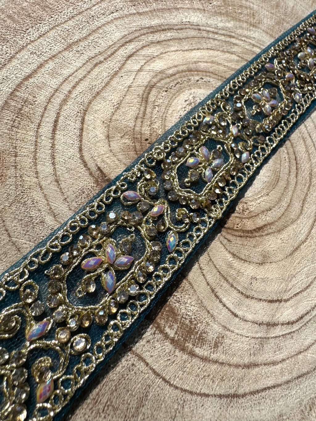 Decorative ribbon with intricate gold and purple pattern on a wooden background