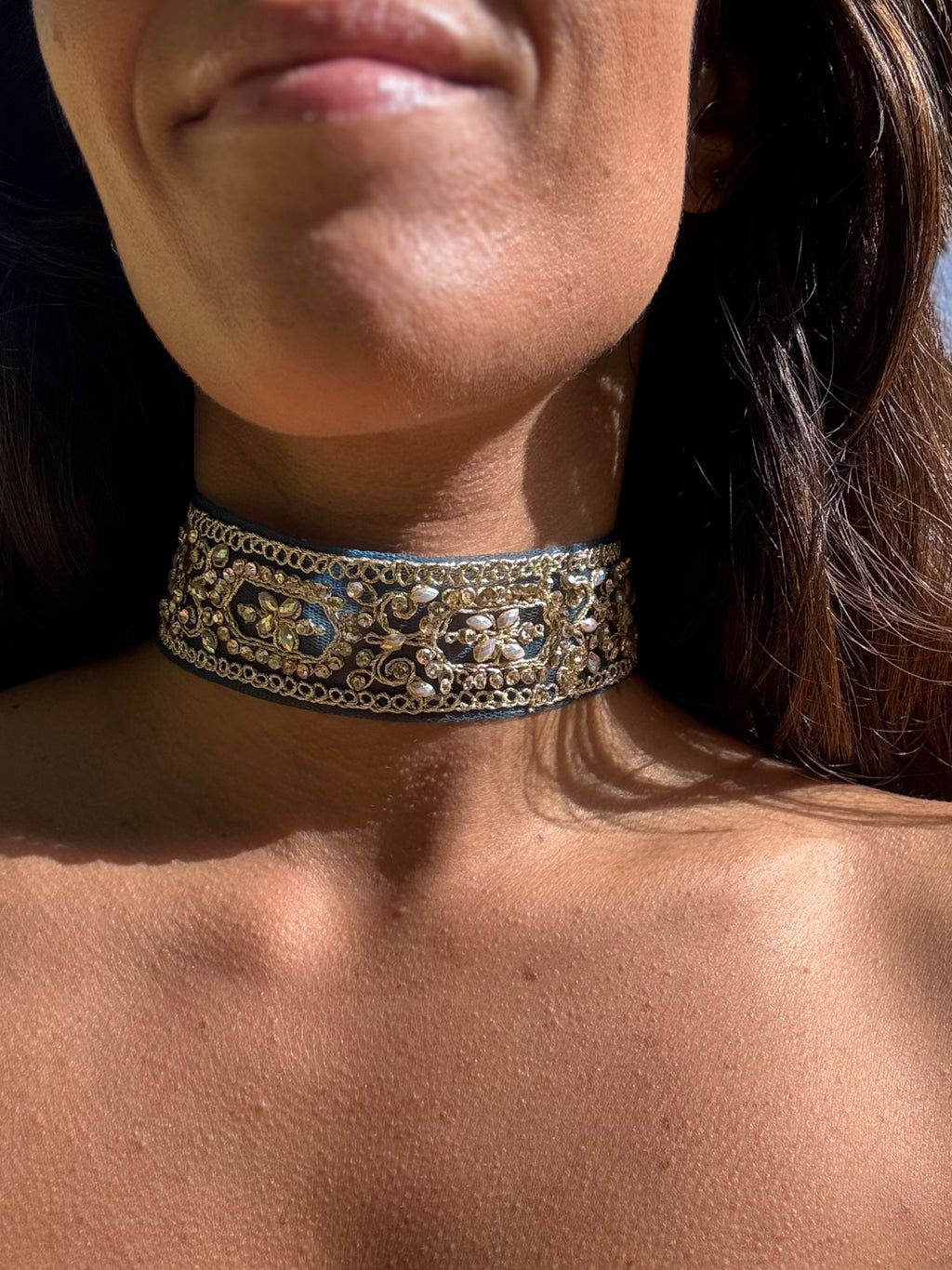Close-up of a person wearing an ornate gold choker necklace.