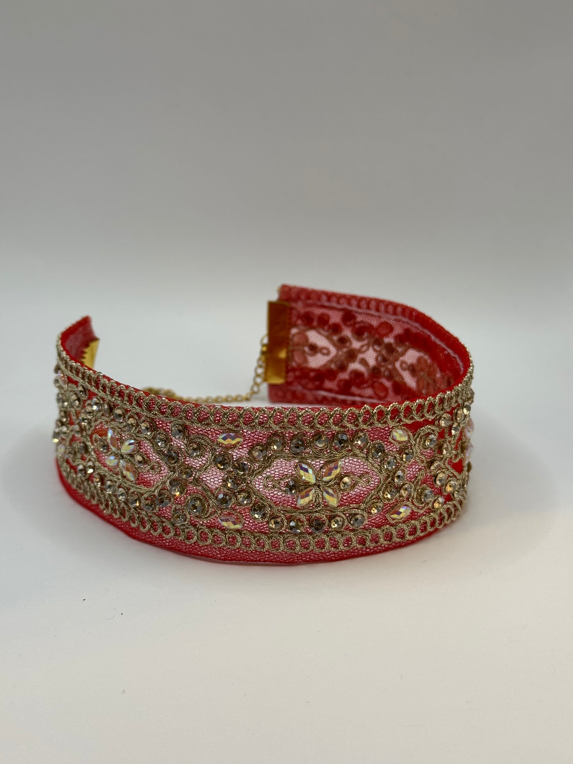 Decorative headband with red fabric and gold embellishments on a white background