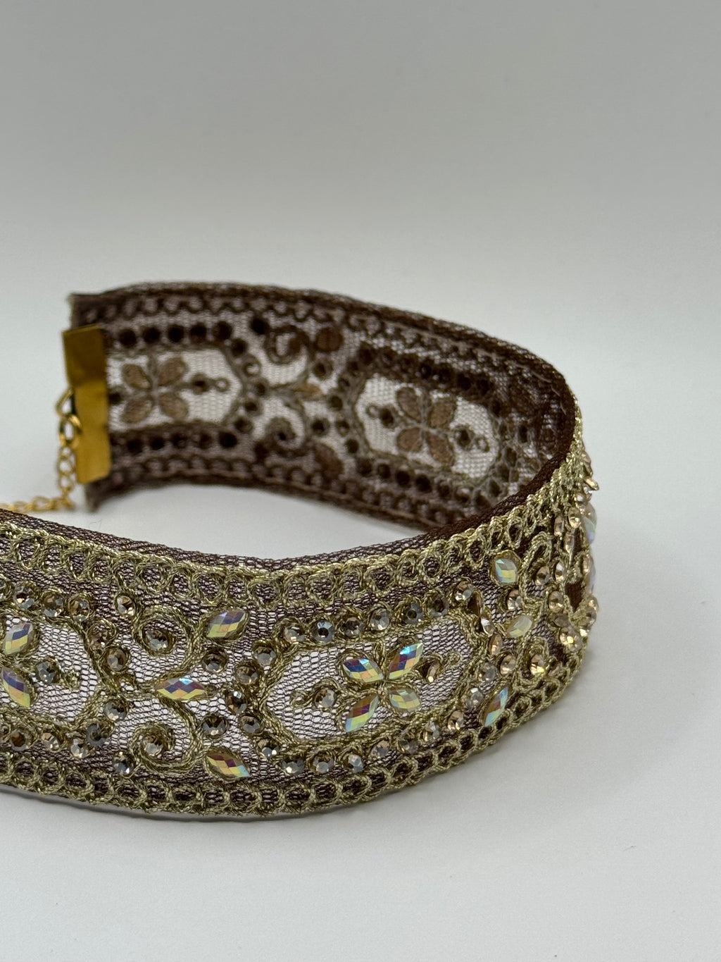 Decorative headband with intricate gold and brown patterns on a white background