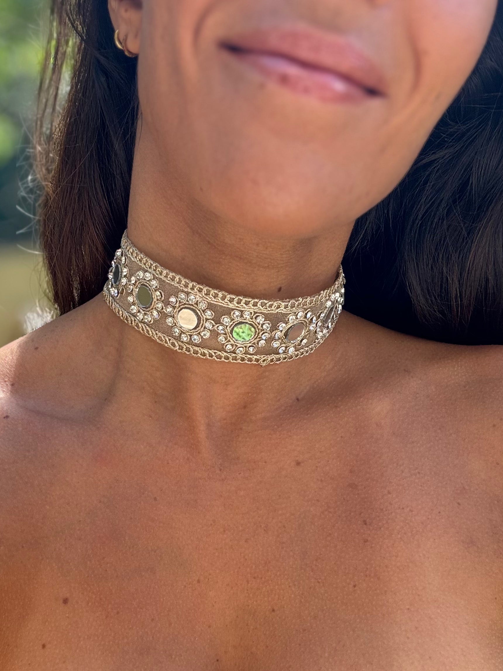 Close-up of a person wearing a decorative silver choker necklace with green gemstones.