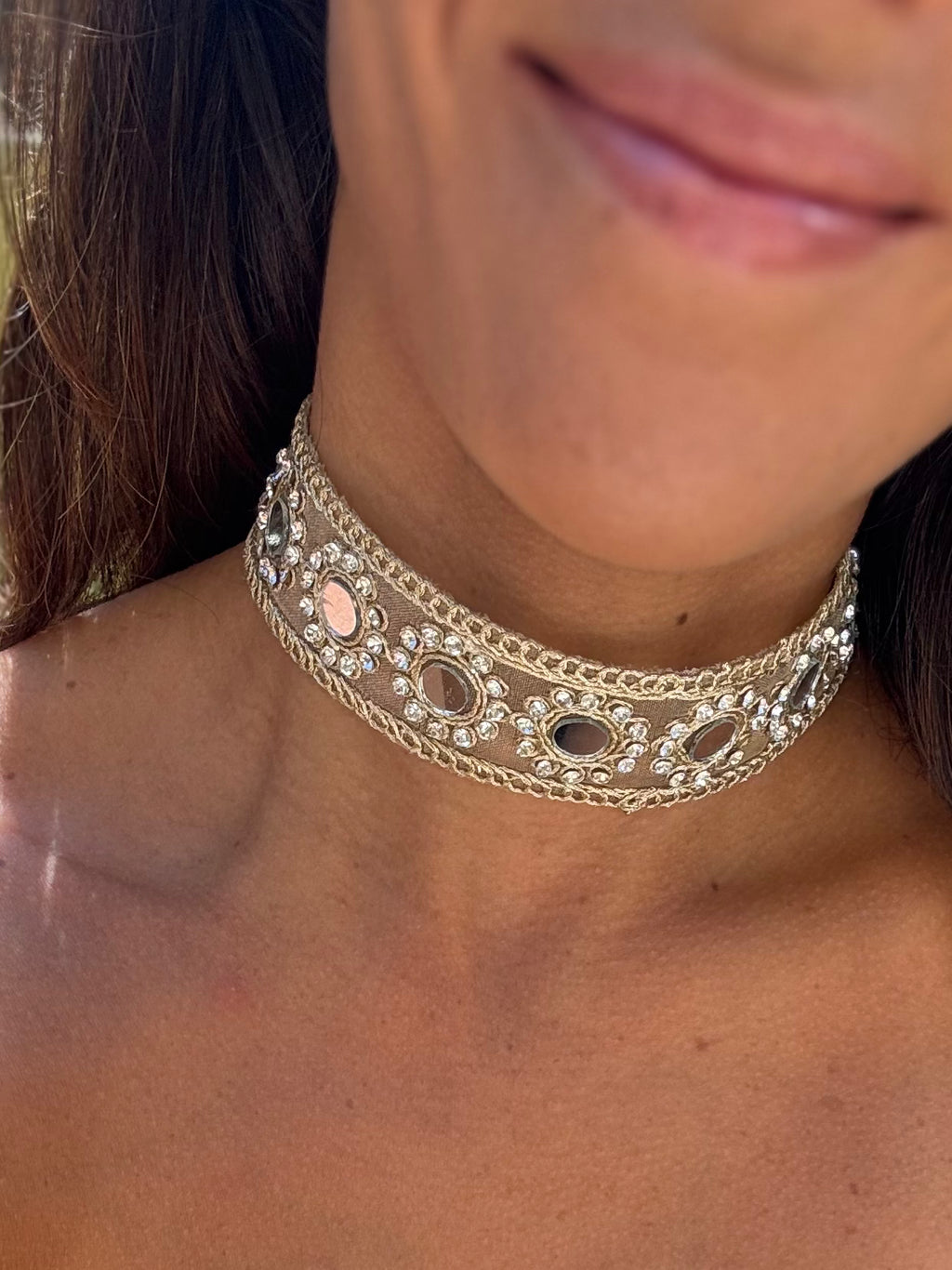 Close-up of a person wearing a gold choker necklace with intricate designs.