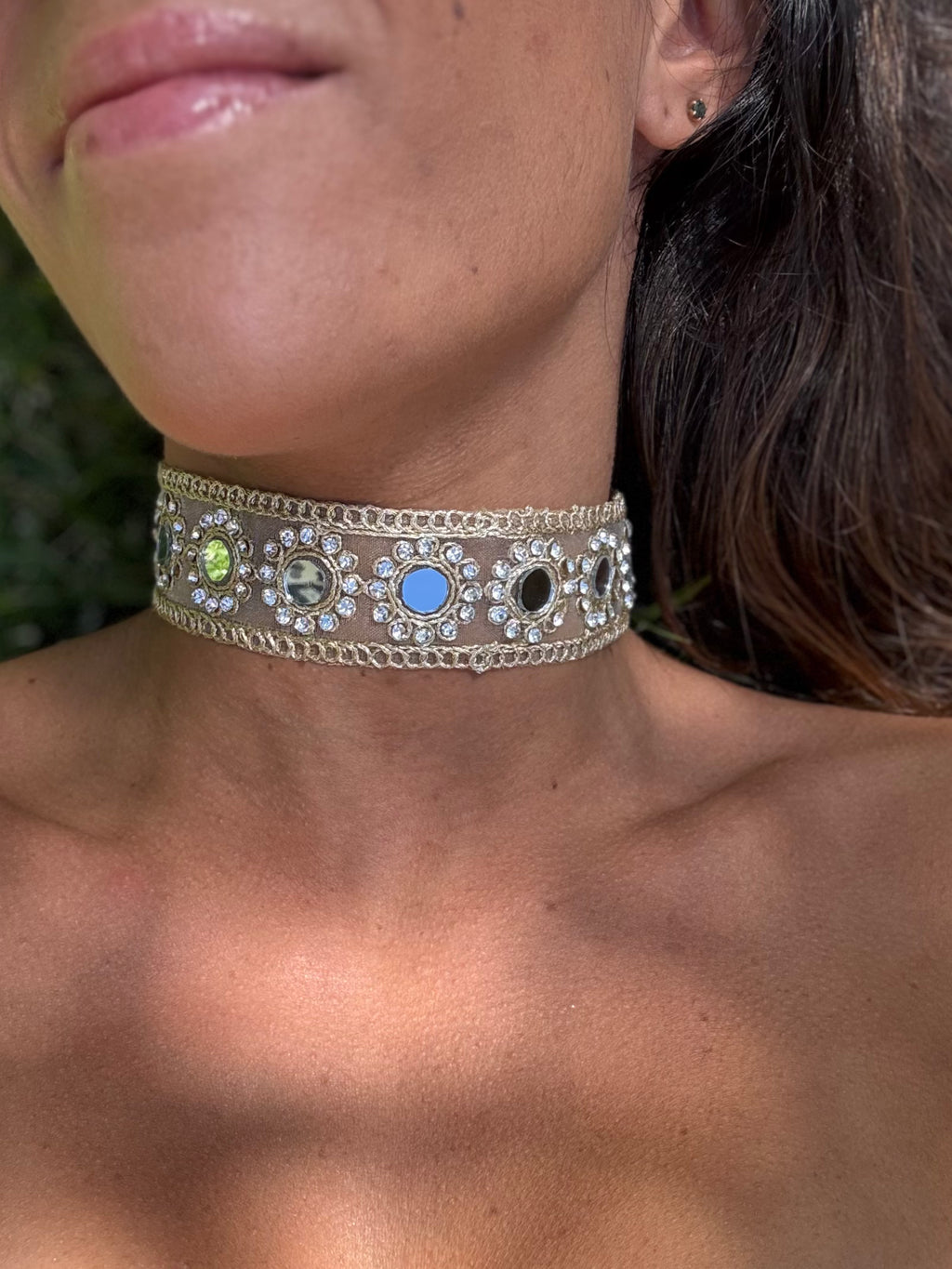 Close-up of a person wearing a decorative choker necklace with colored stones.