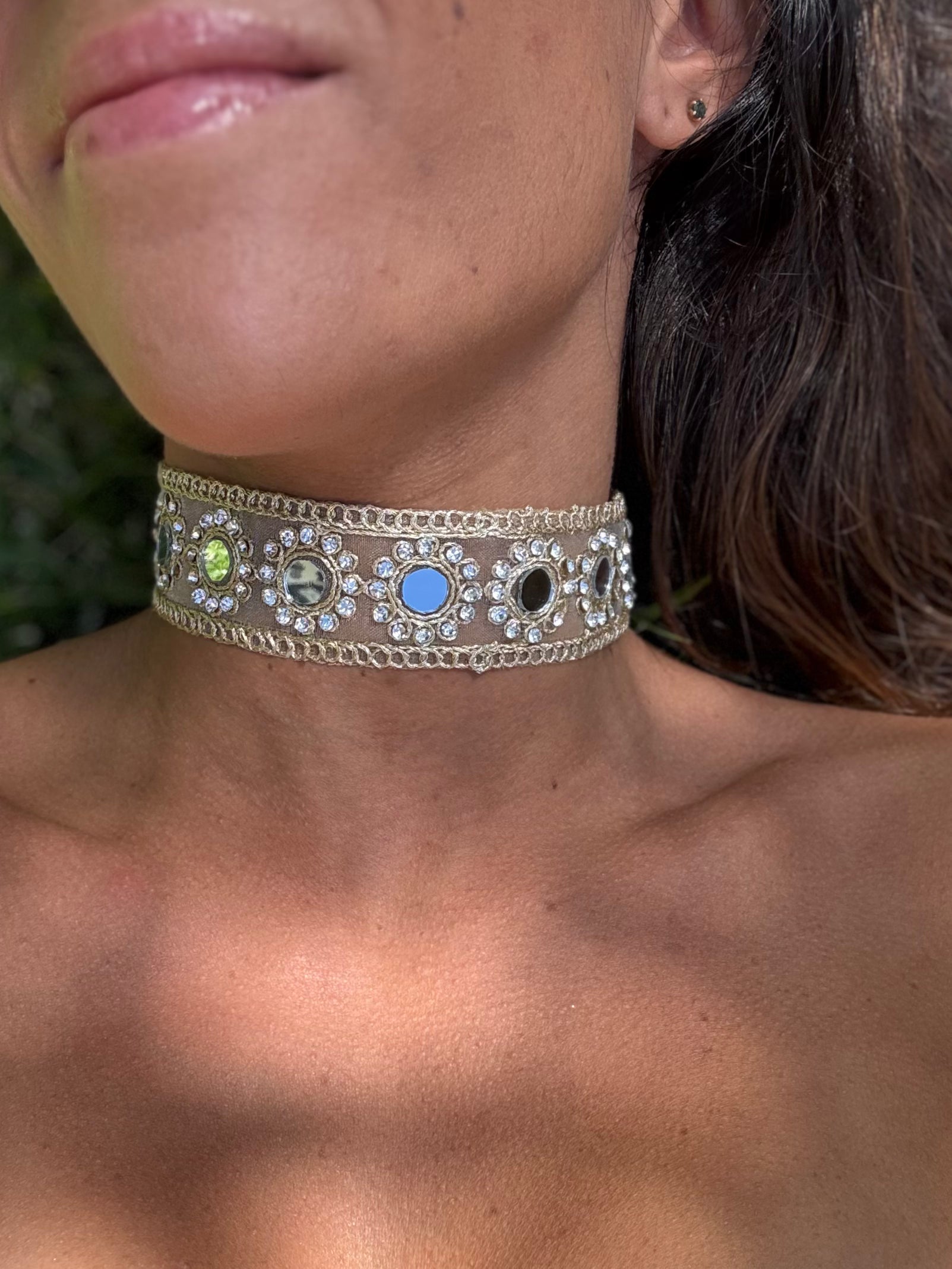 Close-up of a person wearing a decorative choker necklace with colored stones.