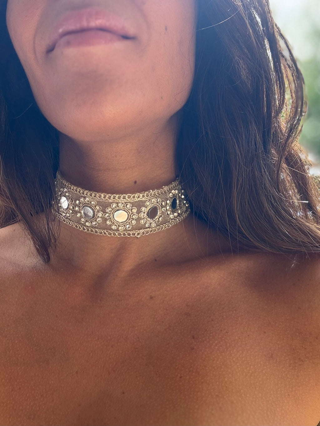 Close-up of a person wearing an ornate choker necklace with a blurred background