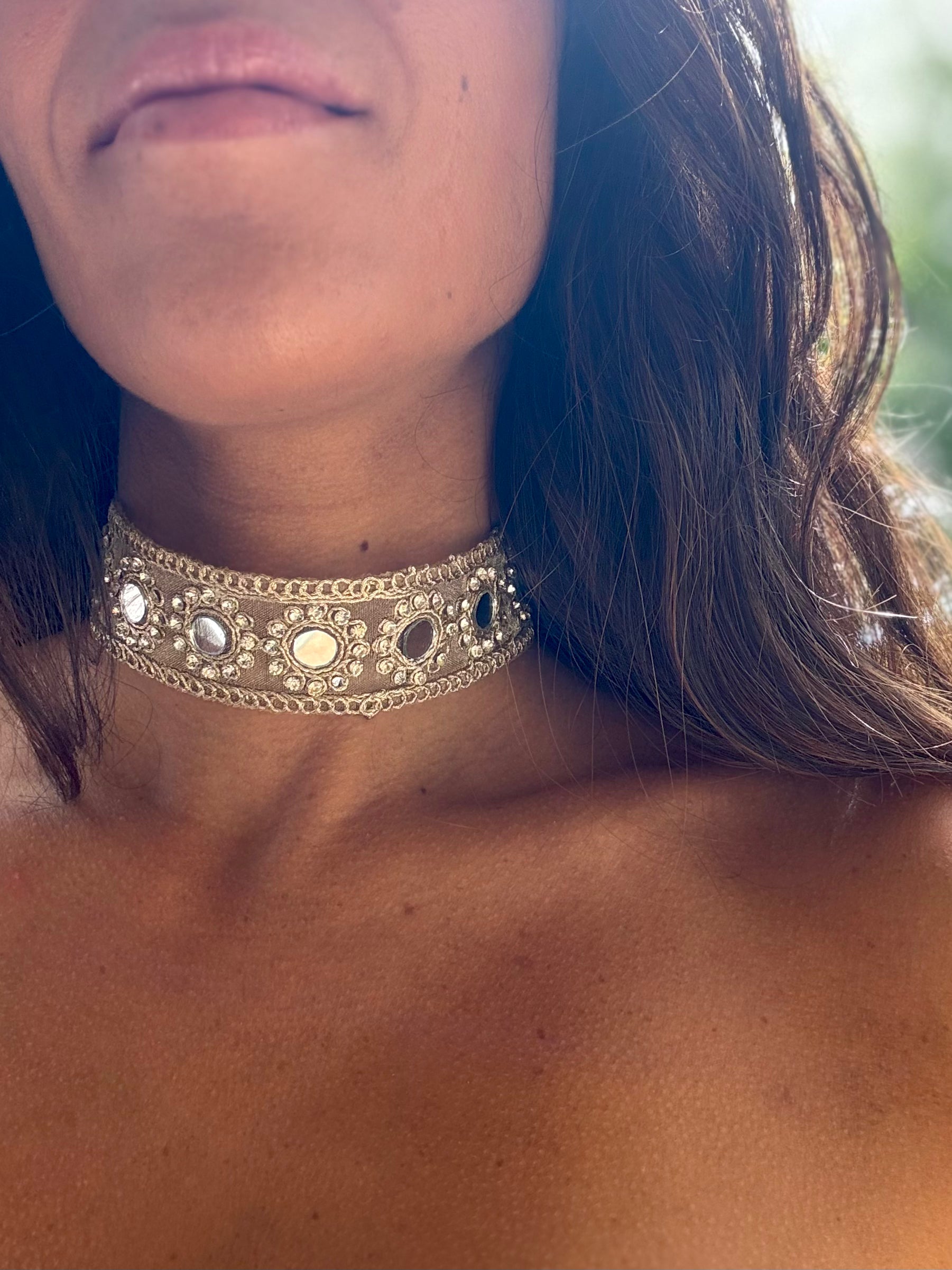 Close-up of a person wearing an ornate choker necklace with a blurred background
