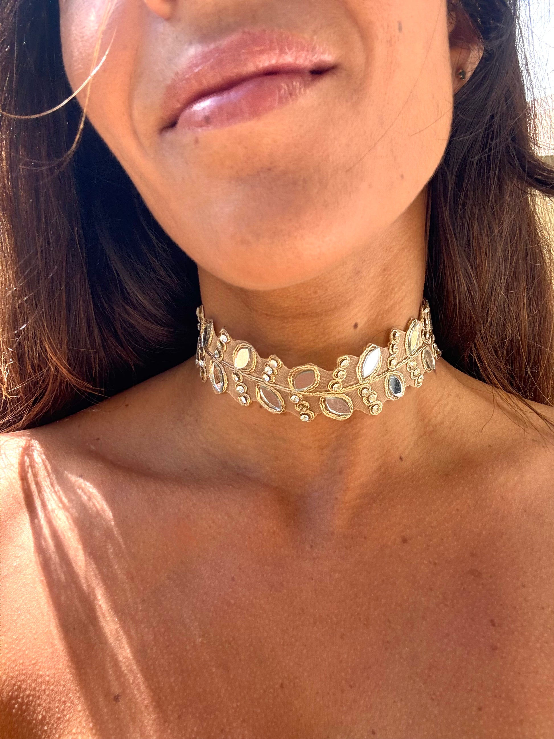 Close-up of a person wearing a gold choker necklace.
