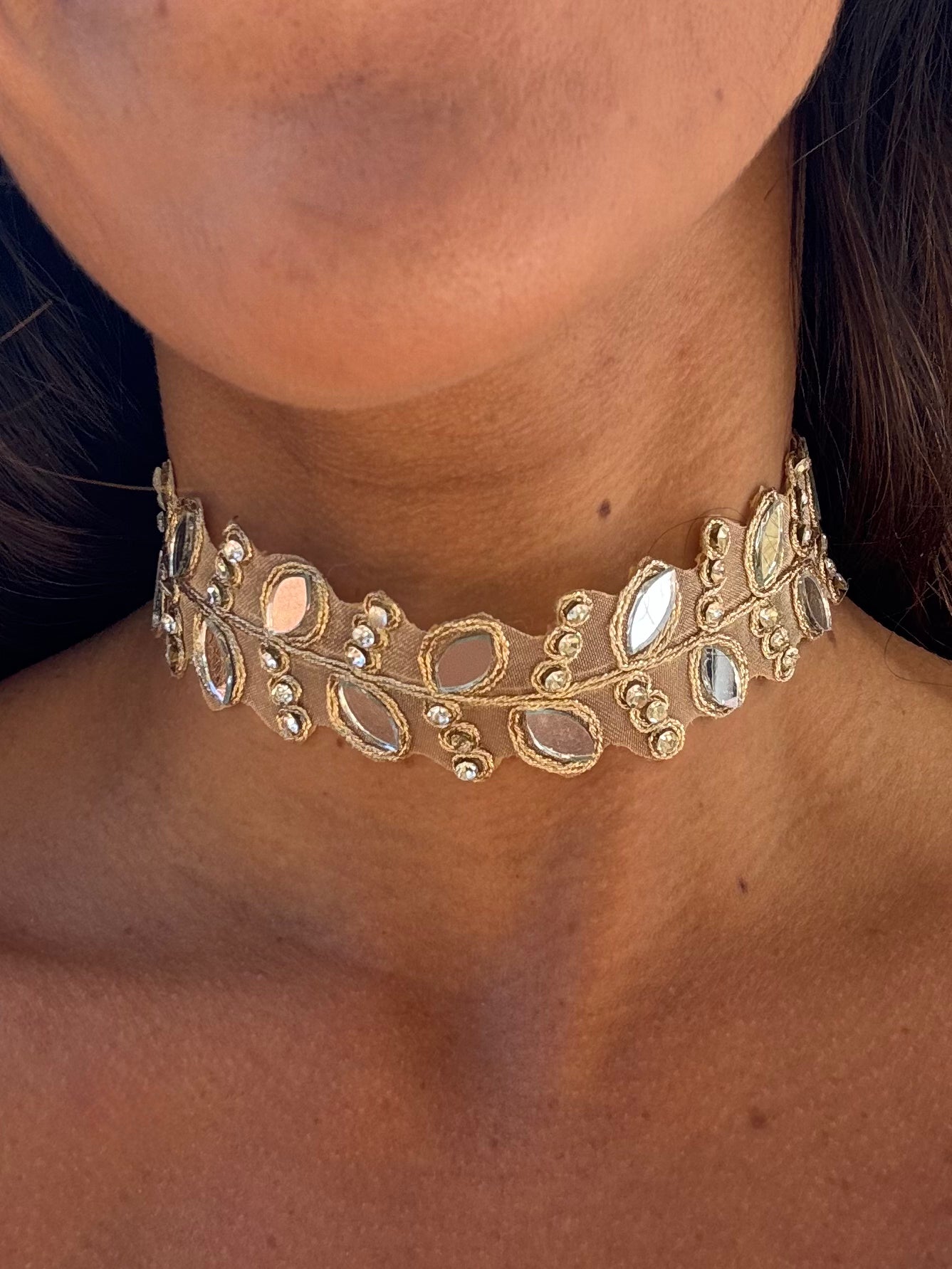 Gold choker necklace with gemstones on a person's neck