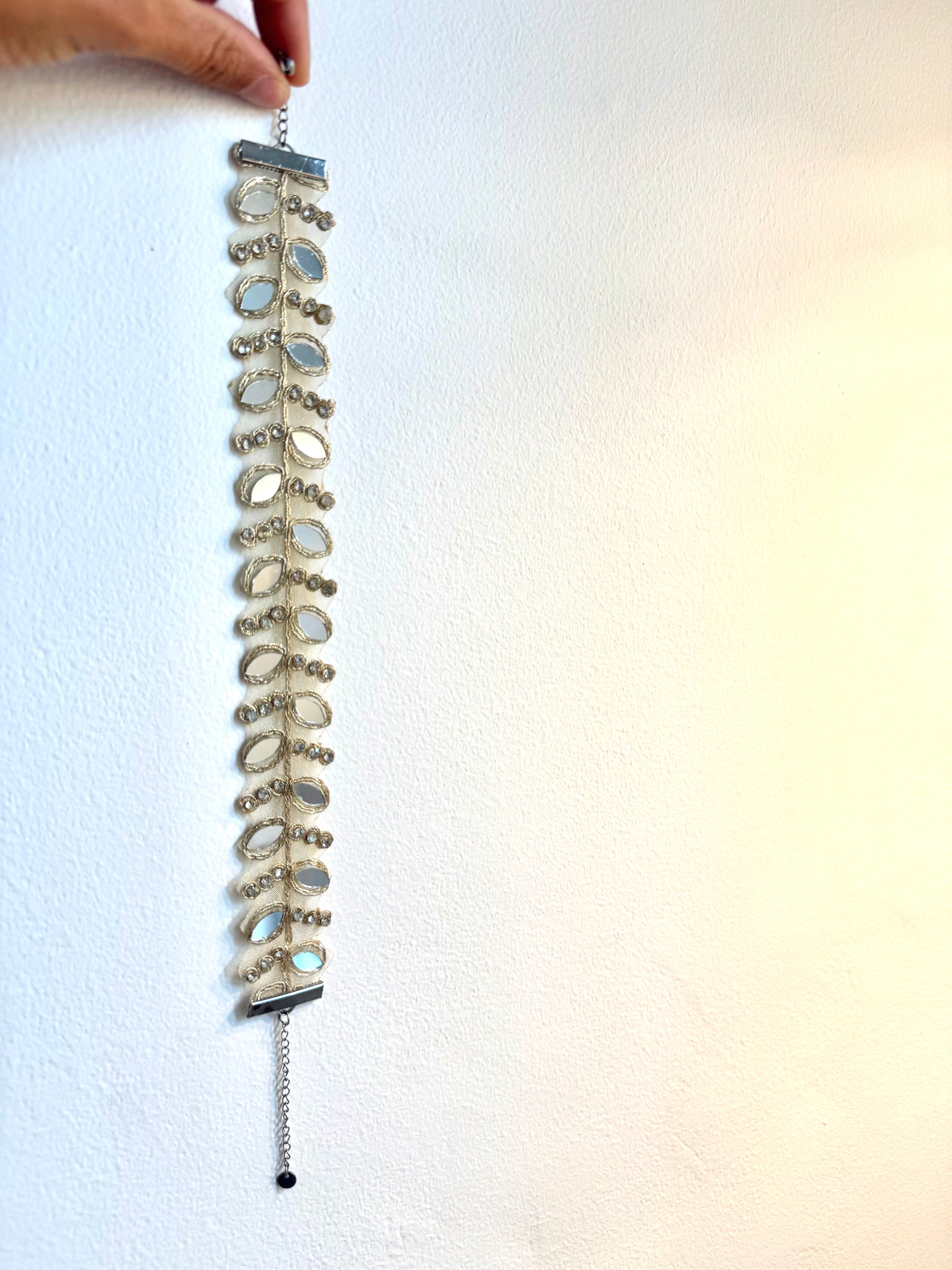 Silver bracelet with gemstones held against a white background