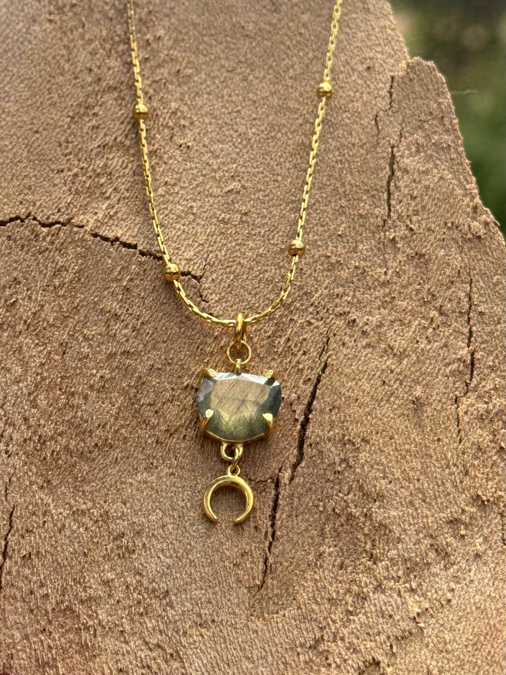 Gold necklace with a pendant on a textured stone surface