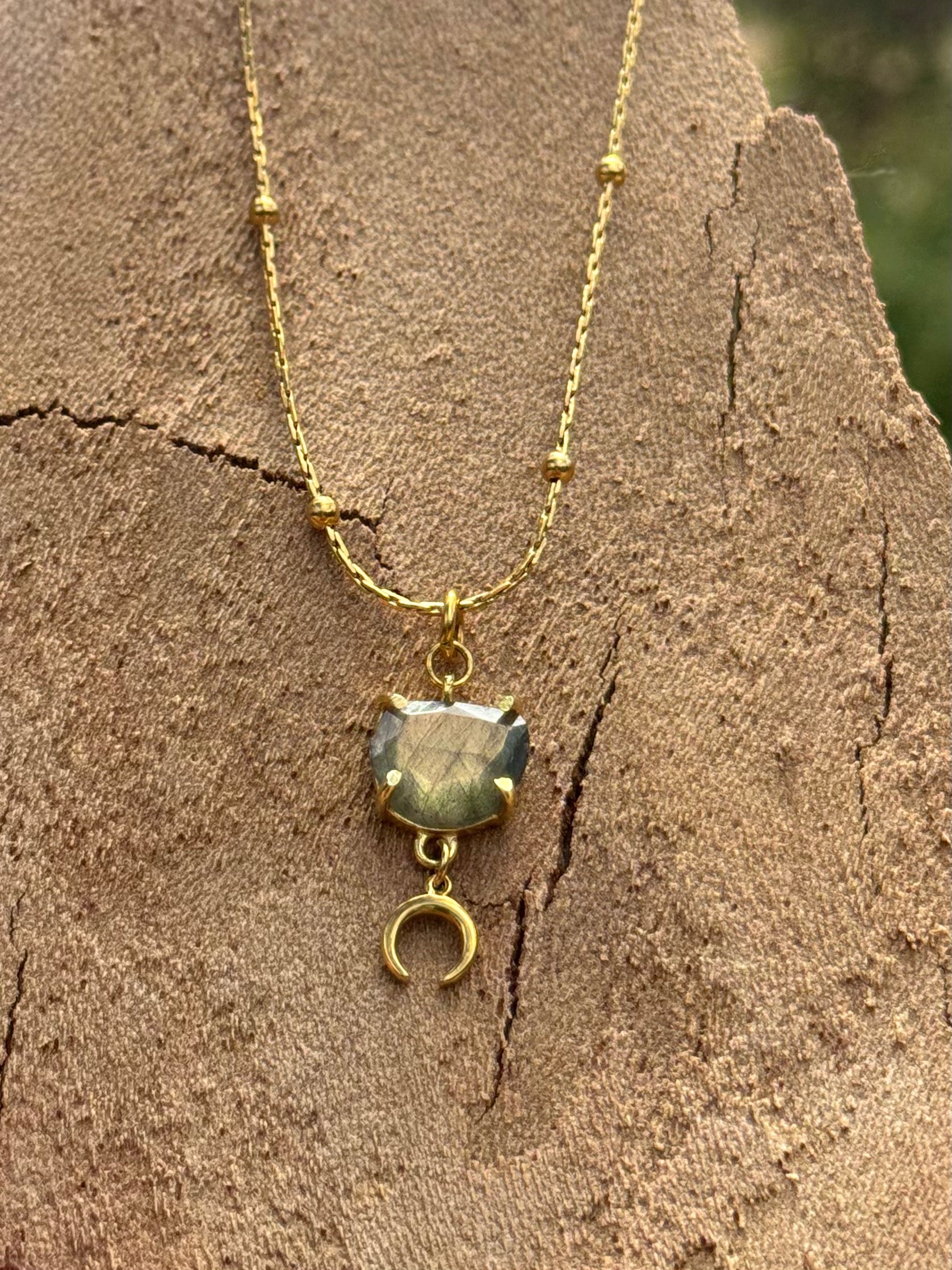 Gold necklace with a pendant on a textured stone surface