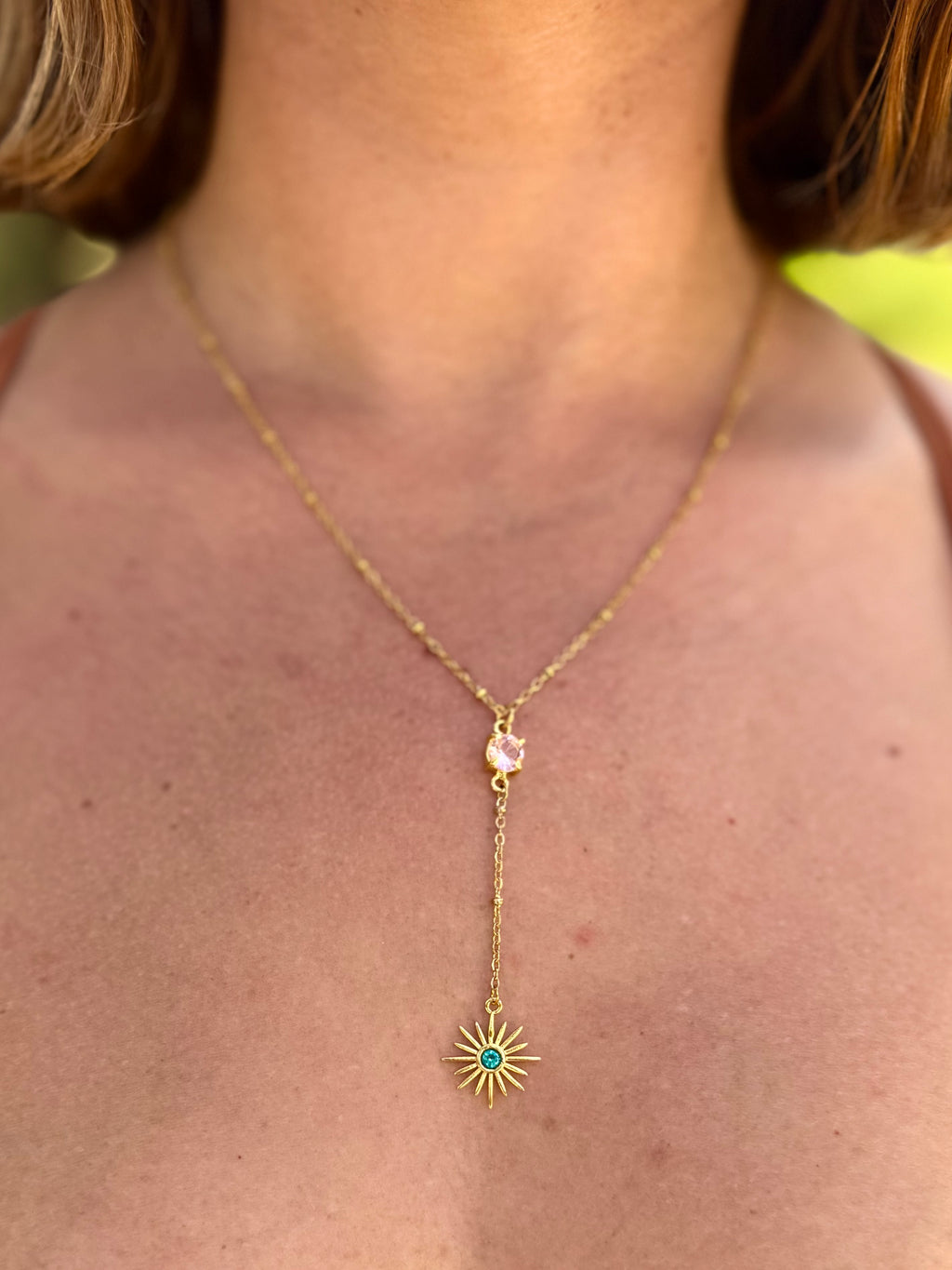 Gold necklace with a star-shaped pendant worn by a person