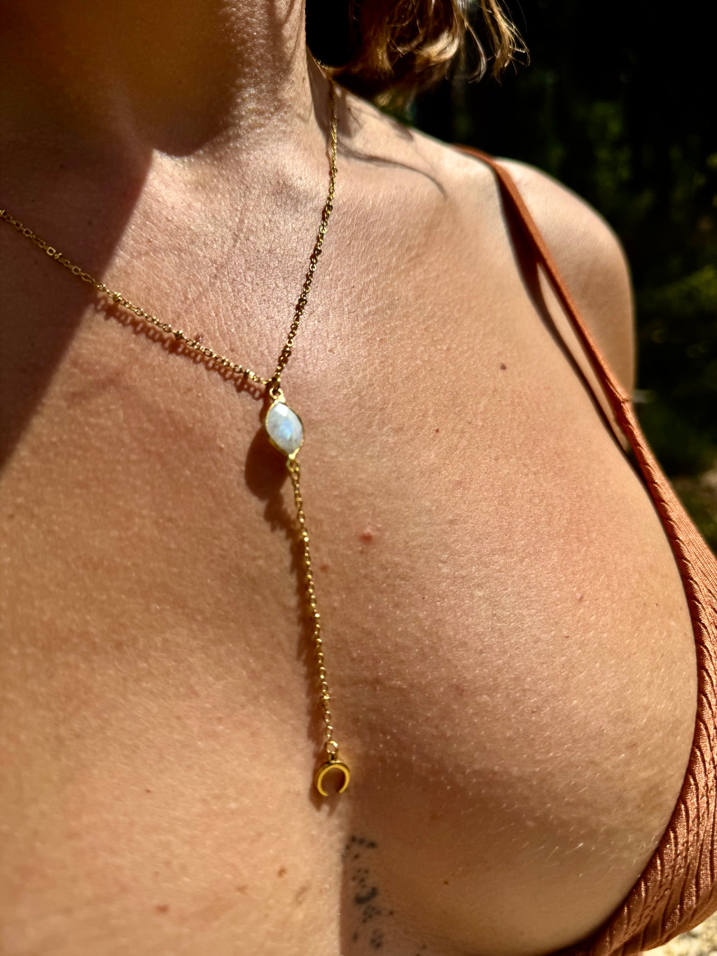 Close-up of a gold necklace with a pendant on a person's neck.