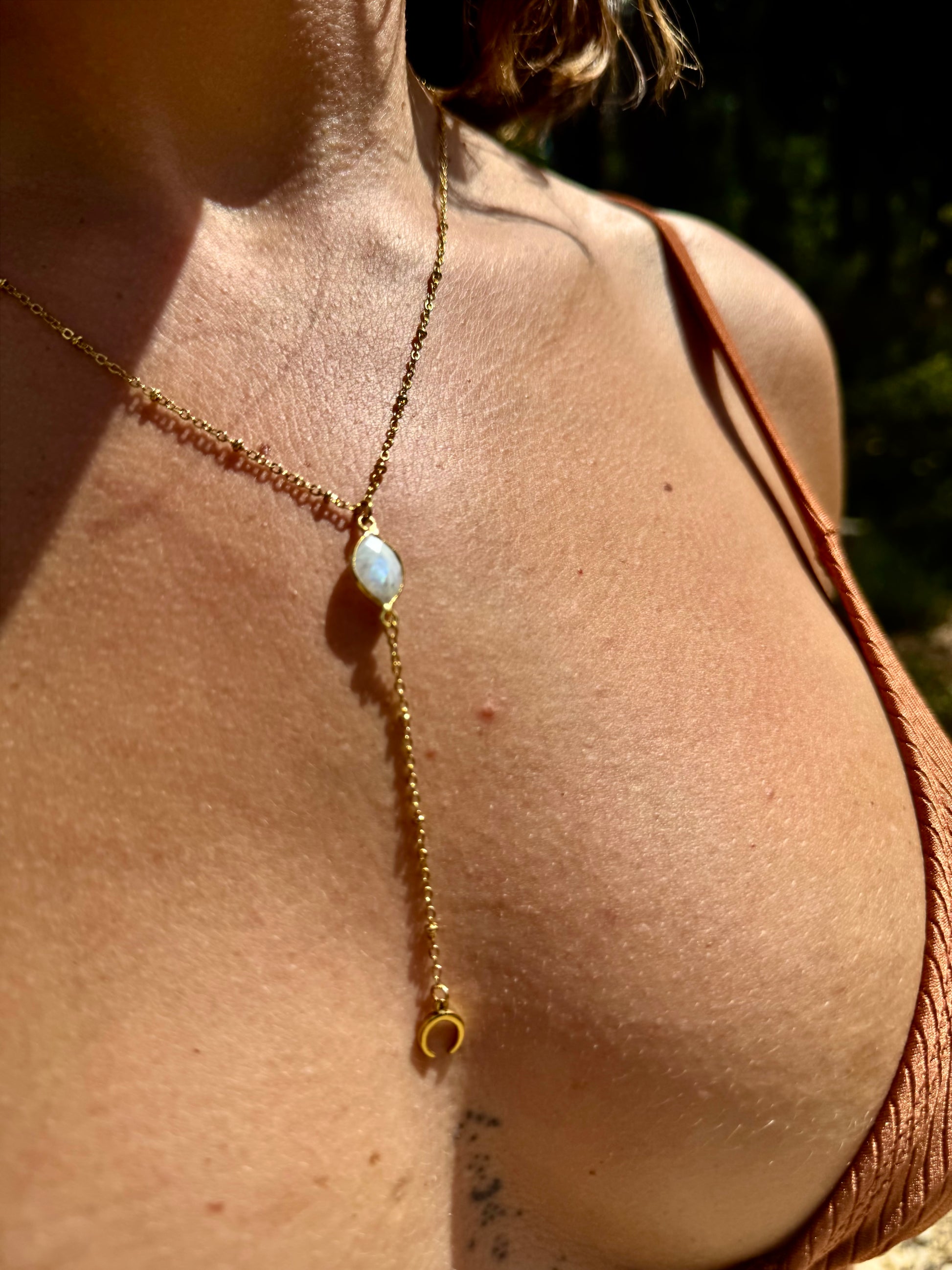 Close-up of a gold necklace with a pendant on a person's neck.