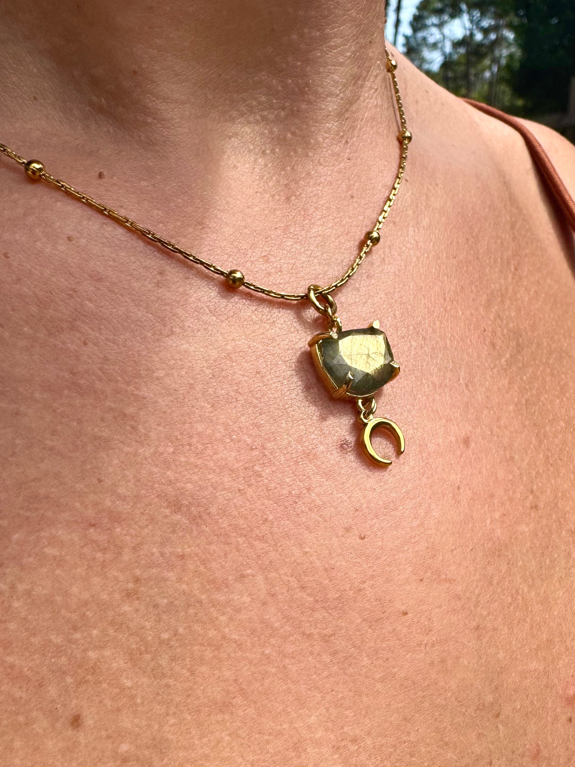 Gold necklace with a pendant on a person's neck
