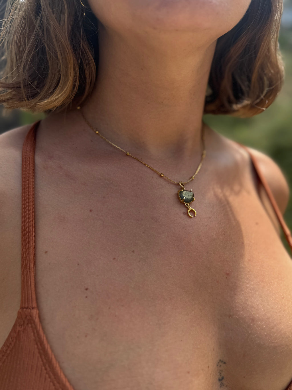 Necklace with a green gemstone pendant worn by a person