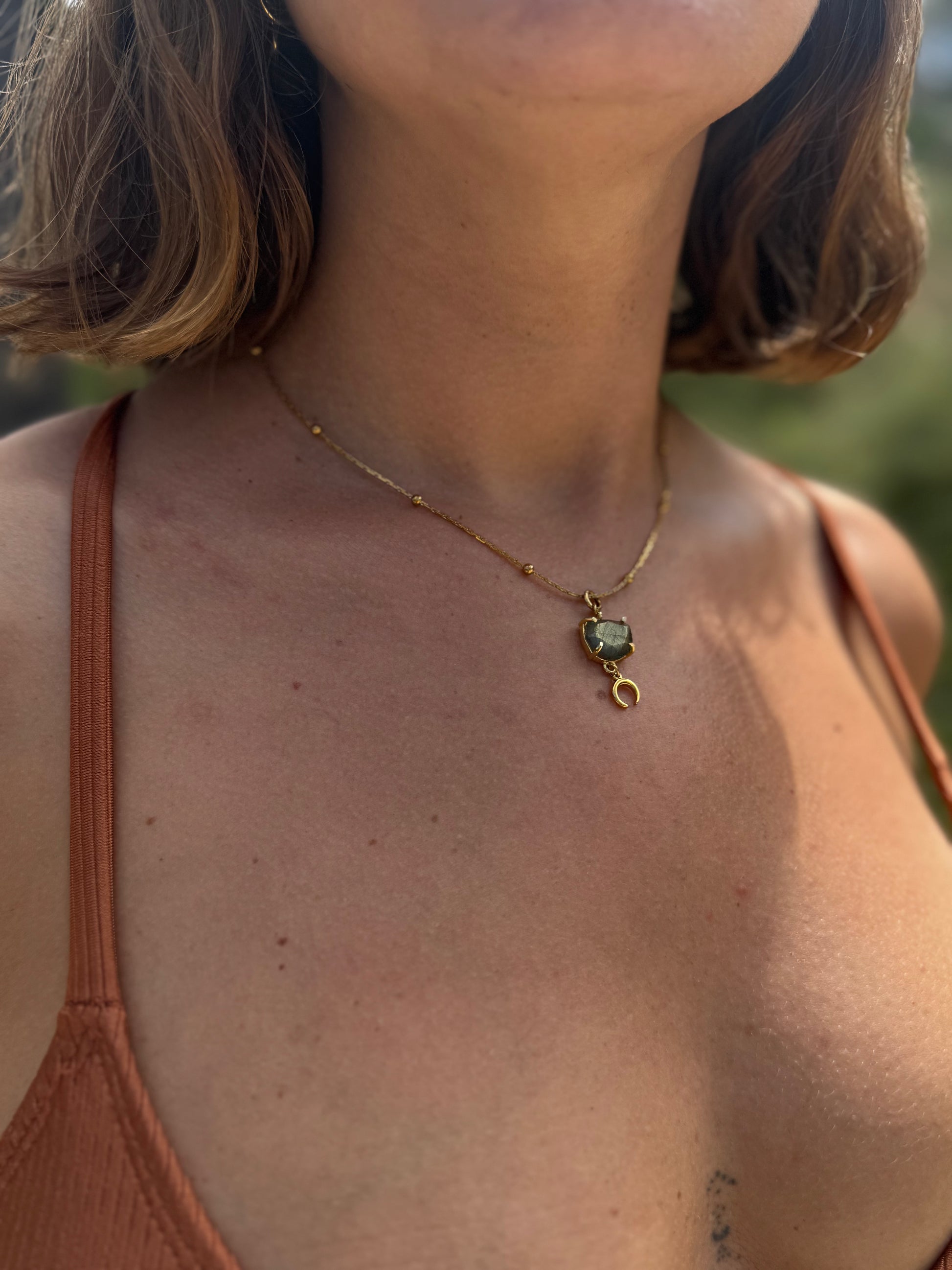 Necklace with a green gemstone pendant worn by a person