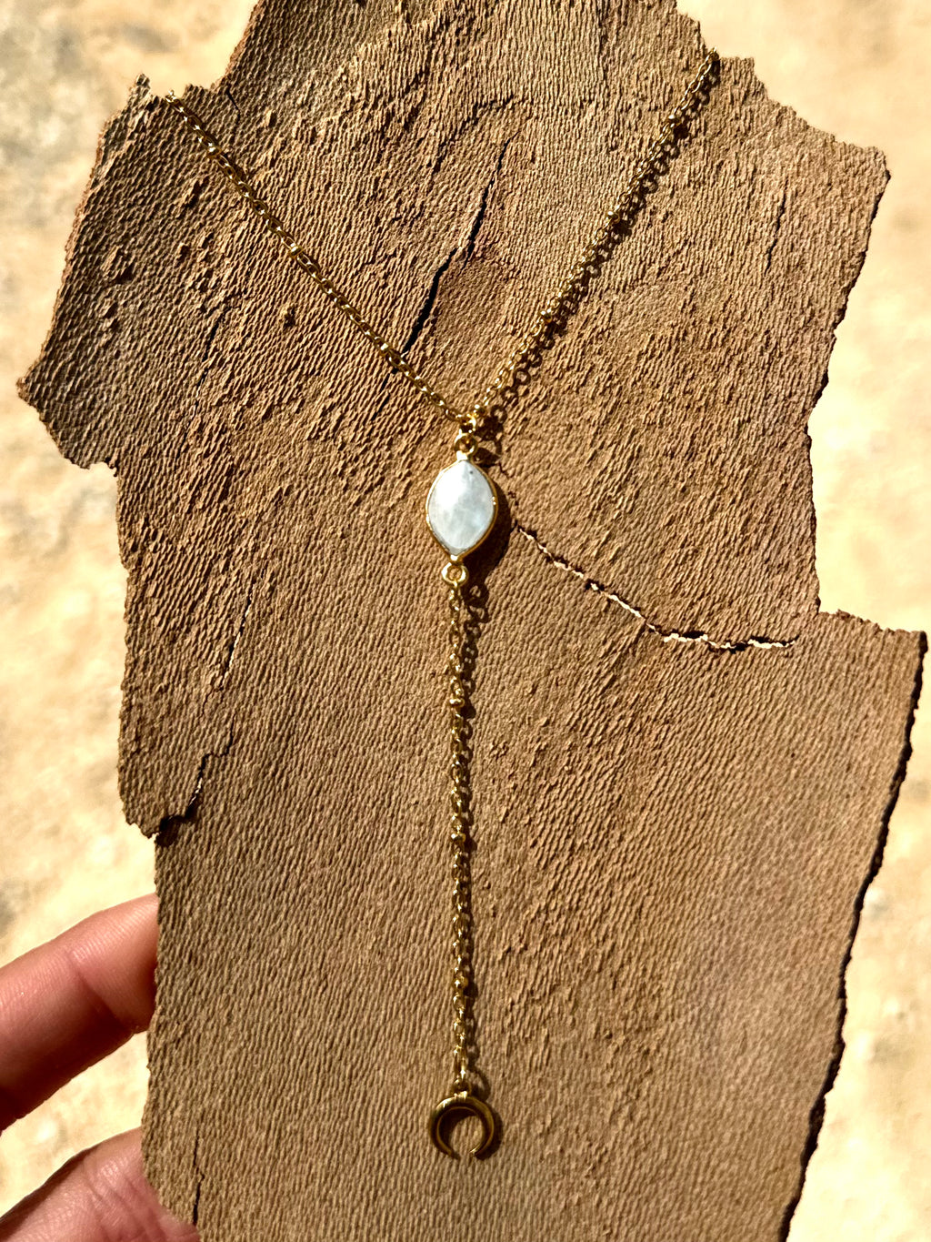Gold necklace with a pendant on a textured brown surface