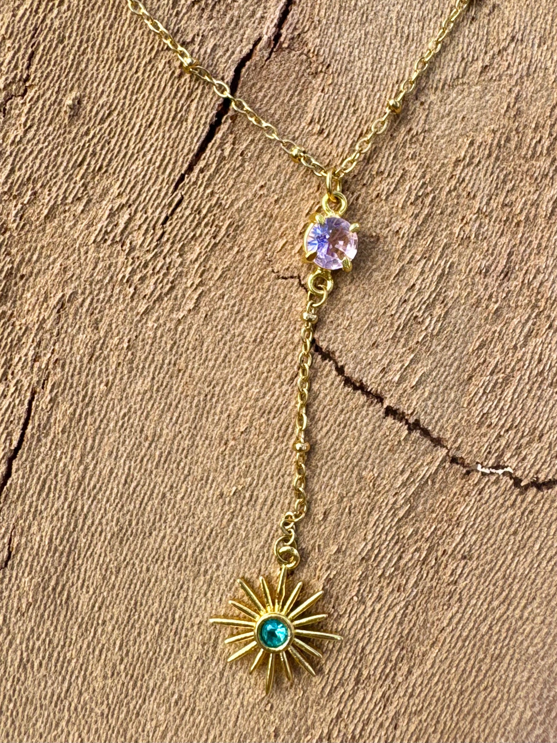 Gold necklace with star-shaped pendant and gemstones on a wooden surface