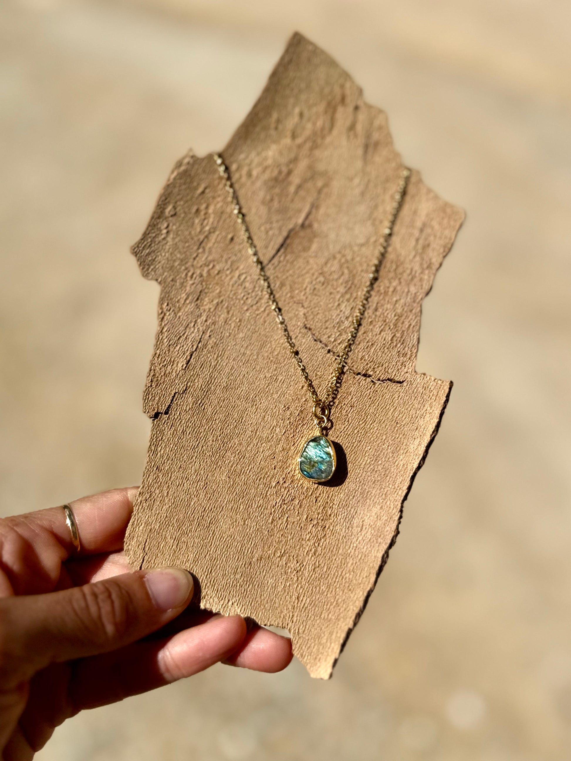 Necklace with a green pendant held on a wooden stand against a blurred background