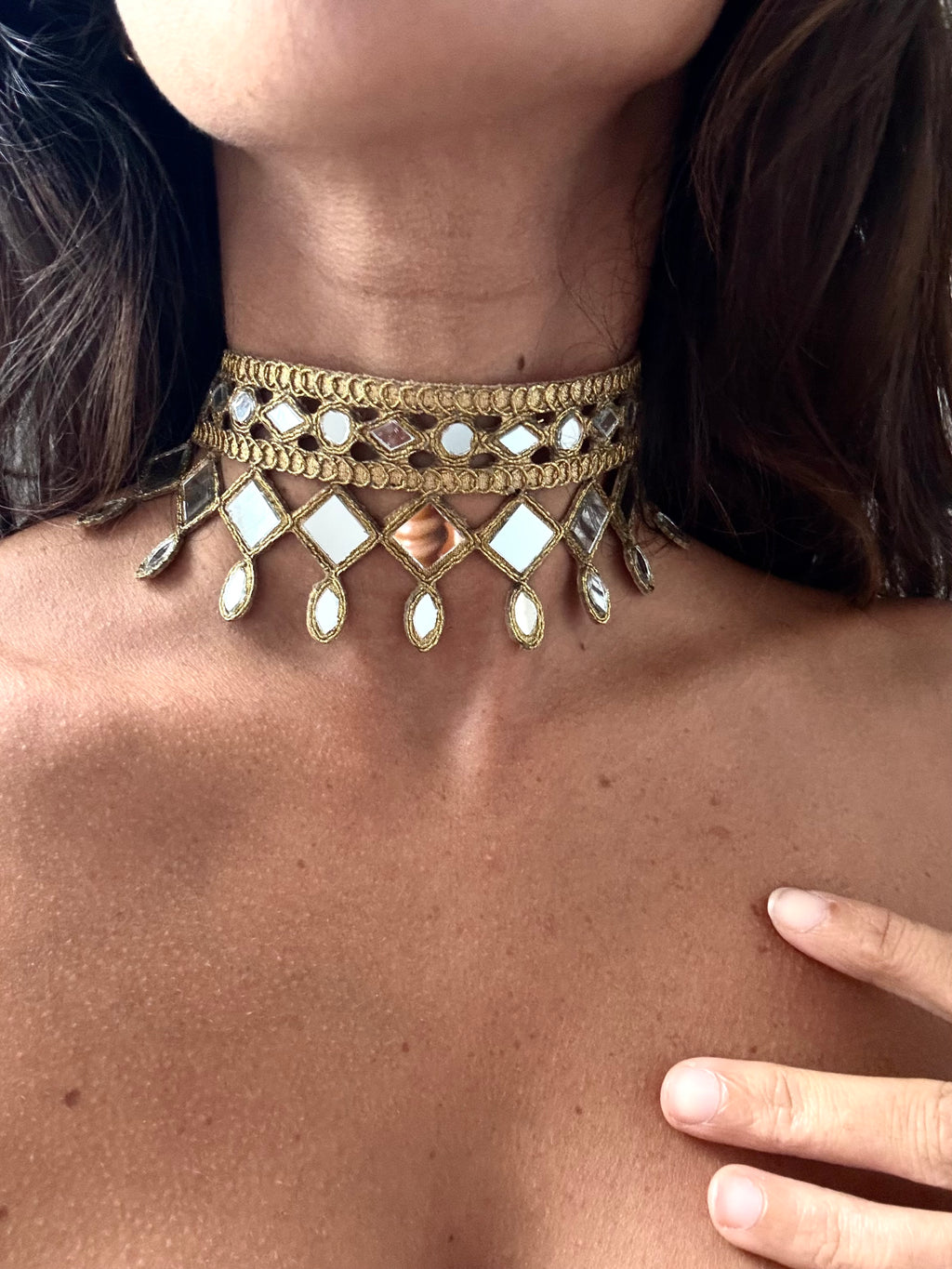Gold choker necklace with reflective stones on a person's neck