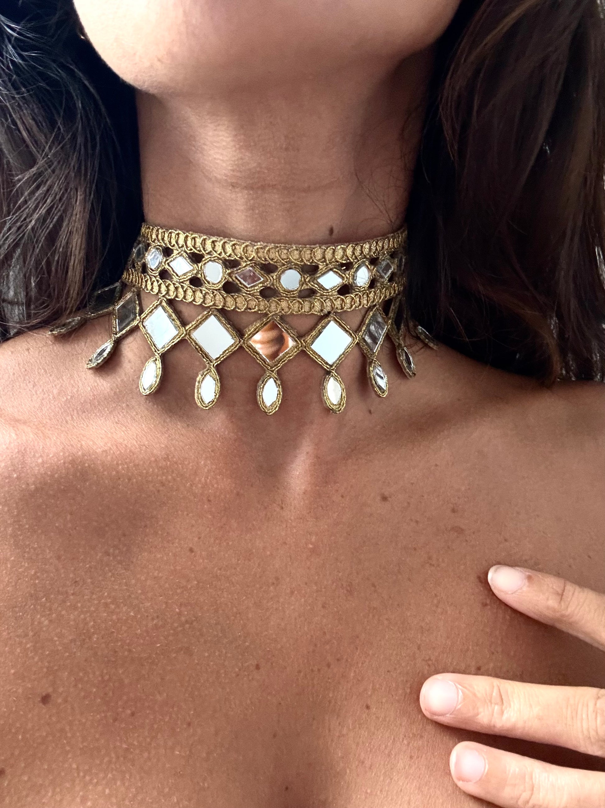 Gold choker necklace with reflective stones on a person's neck