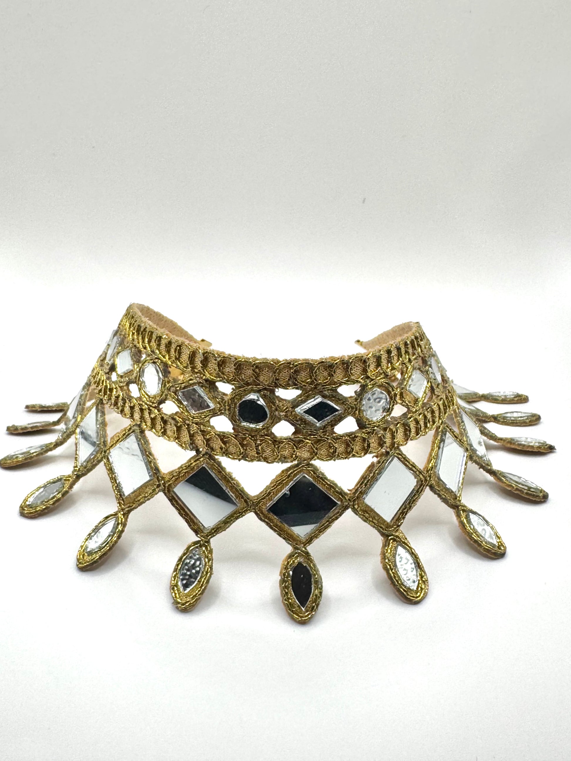 Decorative choker necklace with geometric design and gemstones on a white background