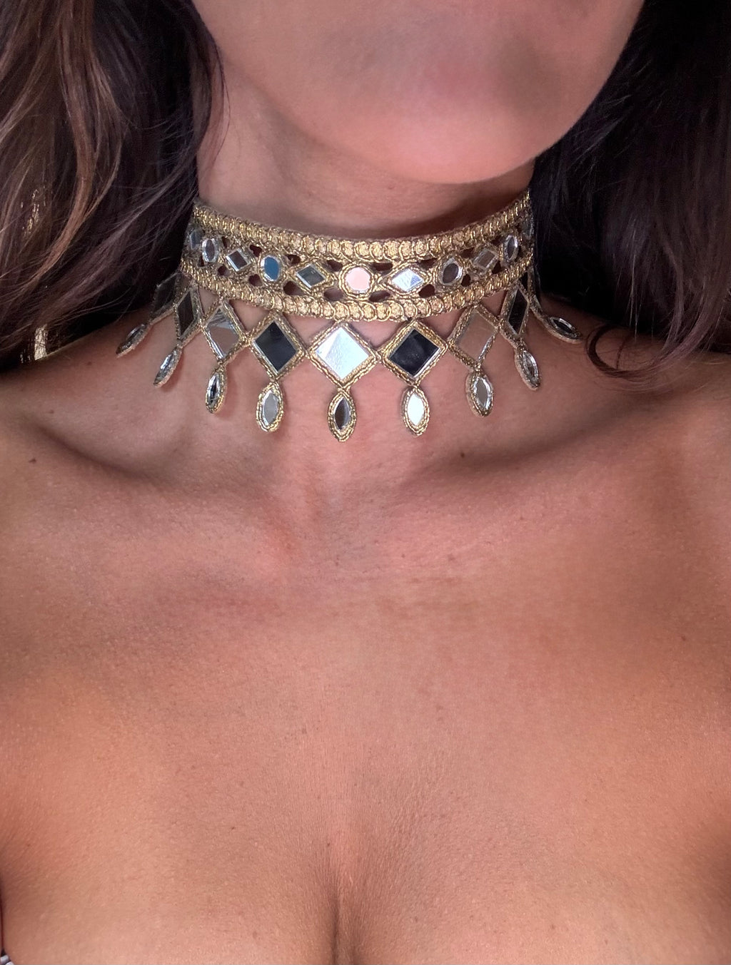 Close-up of a person wearing a decorative gold and gemstone choker necklace.