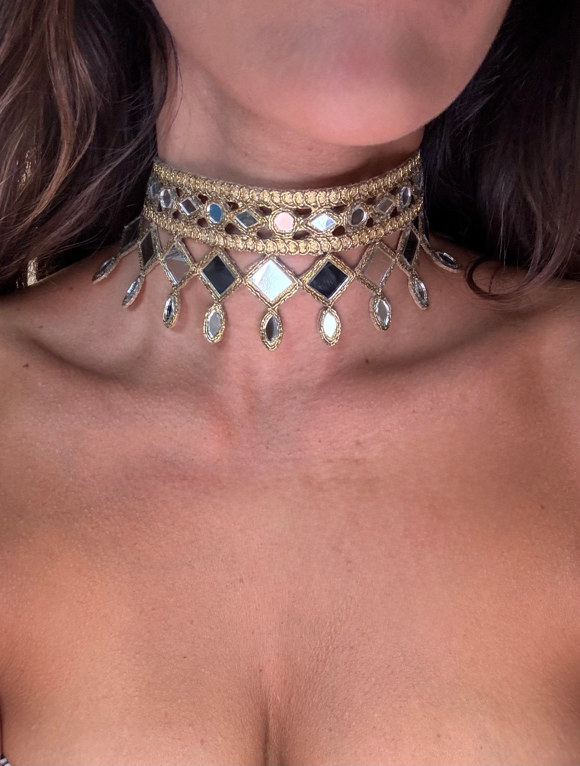 Close-up of a person wearing a decorative gold and gemstone choker necklace.