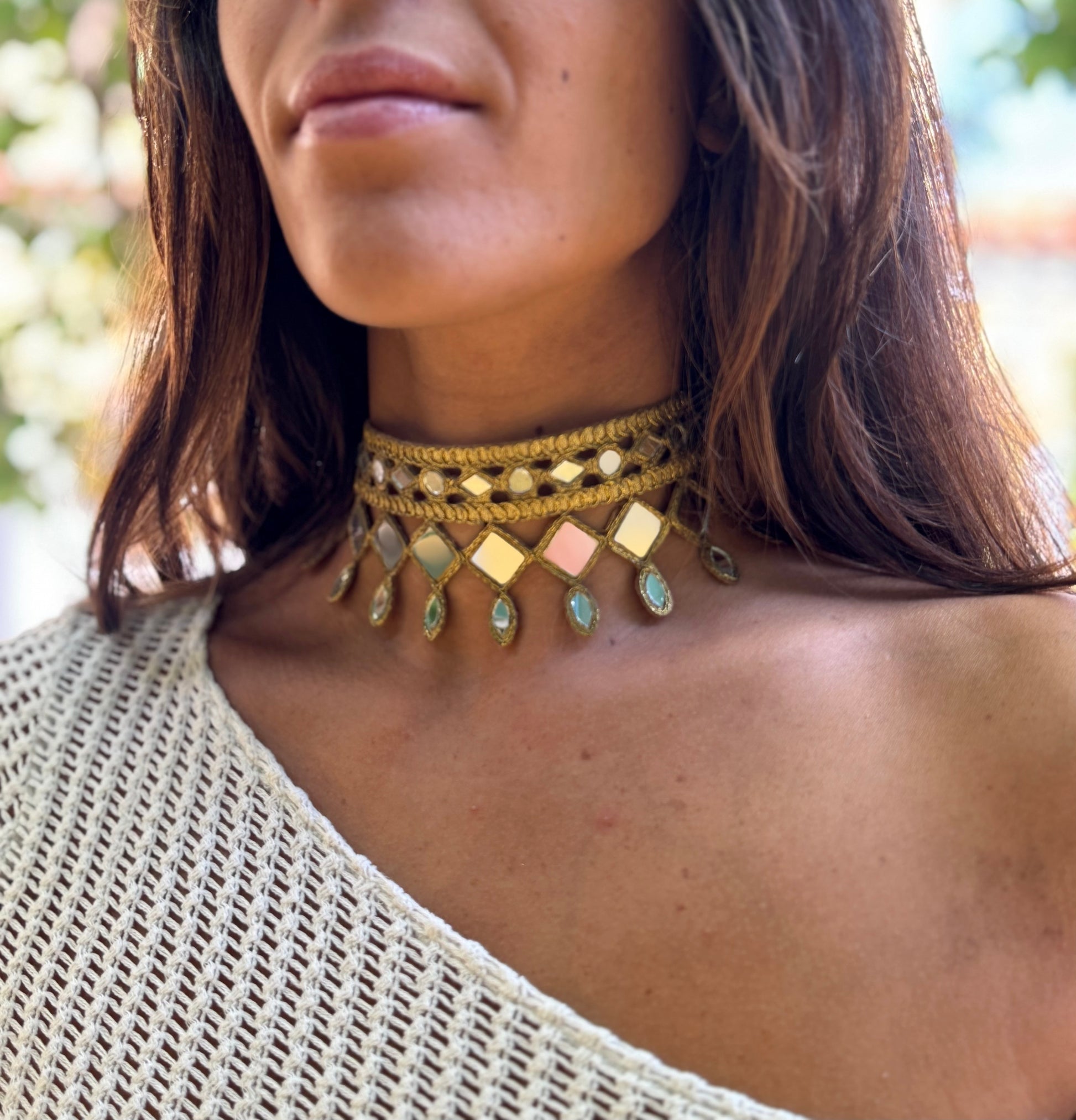 Close-up of a person wearing a gold choker necklace with geometric designs.